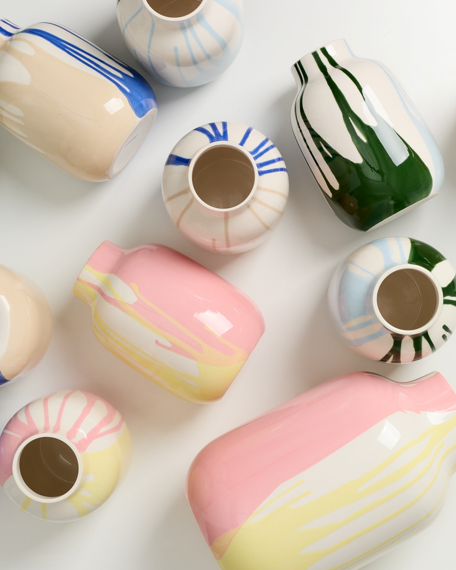 Verschiedene bunte Vasen mit abstrakten Mustern liegen auf einer weißen Oberfläche.