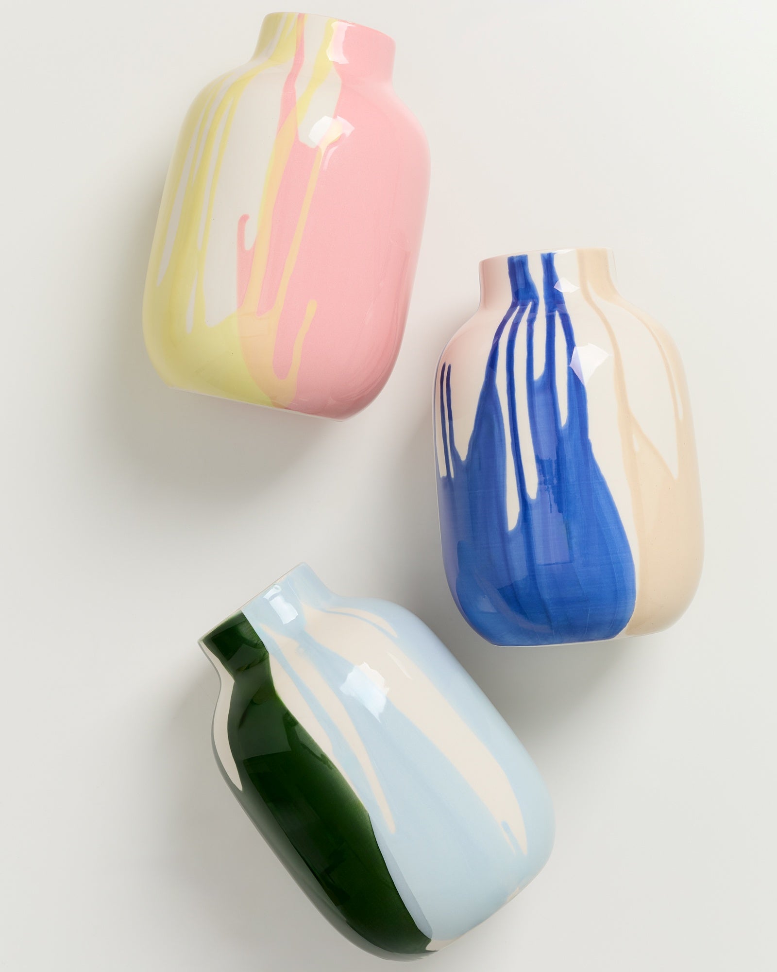 Drei dekorative Vasen mit bunten, fließenden Farbmustern auf hellem Hintergrund.