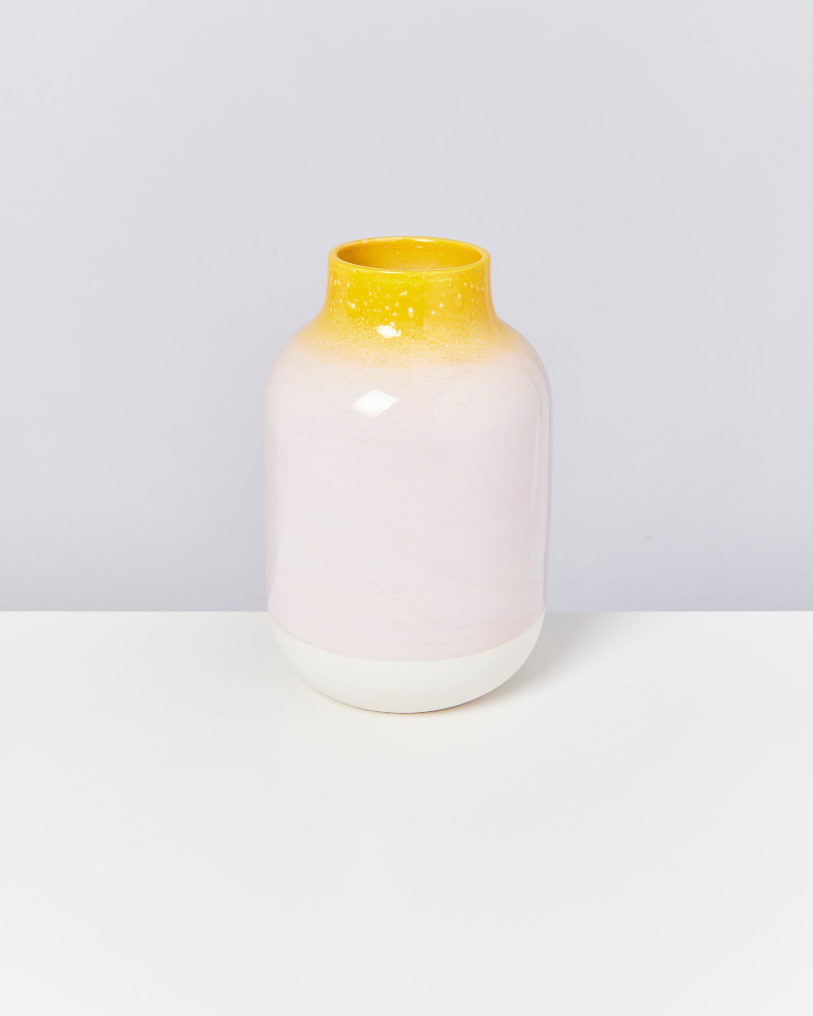 Eine Vase mit gelbem und weißem Farbverlauf steht auf einem weißen Hintergrund.
