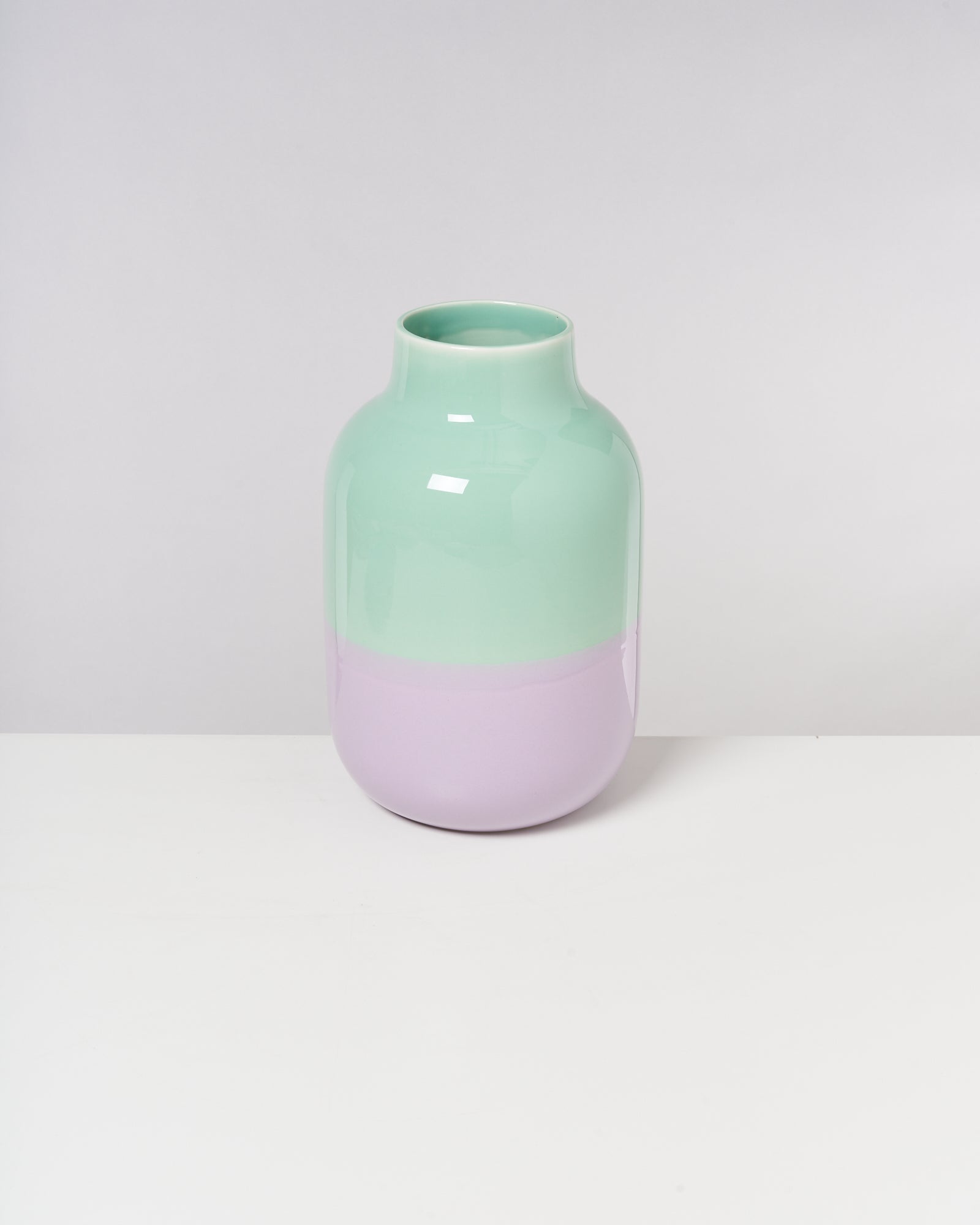 Zweifarbige Vase mit mintgrünem oberen Teil und lila unterem Teil, auf weißem Hintergrund.