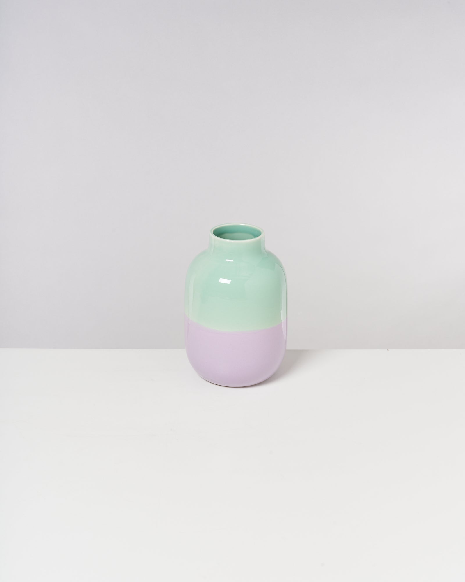 Zweifarbige Vase in Mintgrün und Lavendel auf weißem Hintergrund.