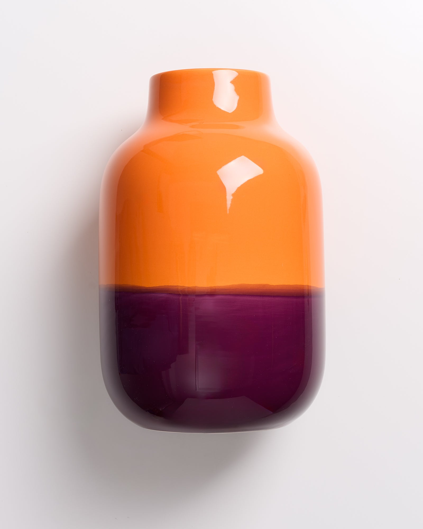 Orange-violette Vase auf weißem Hintergrund.