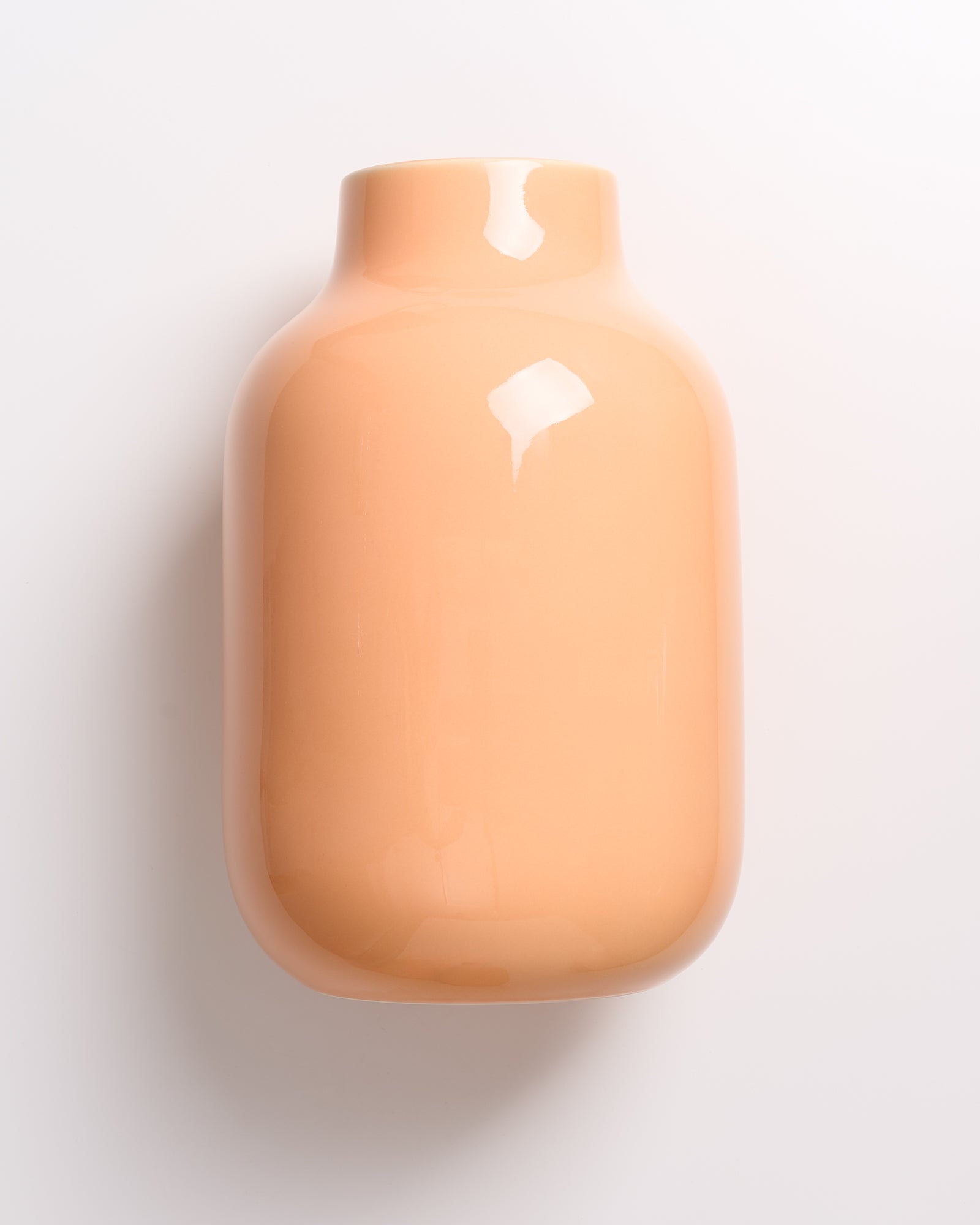 Beige, glänzende keramische Vase vor einem weißen Hintergrund.