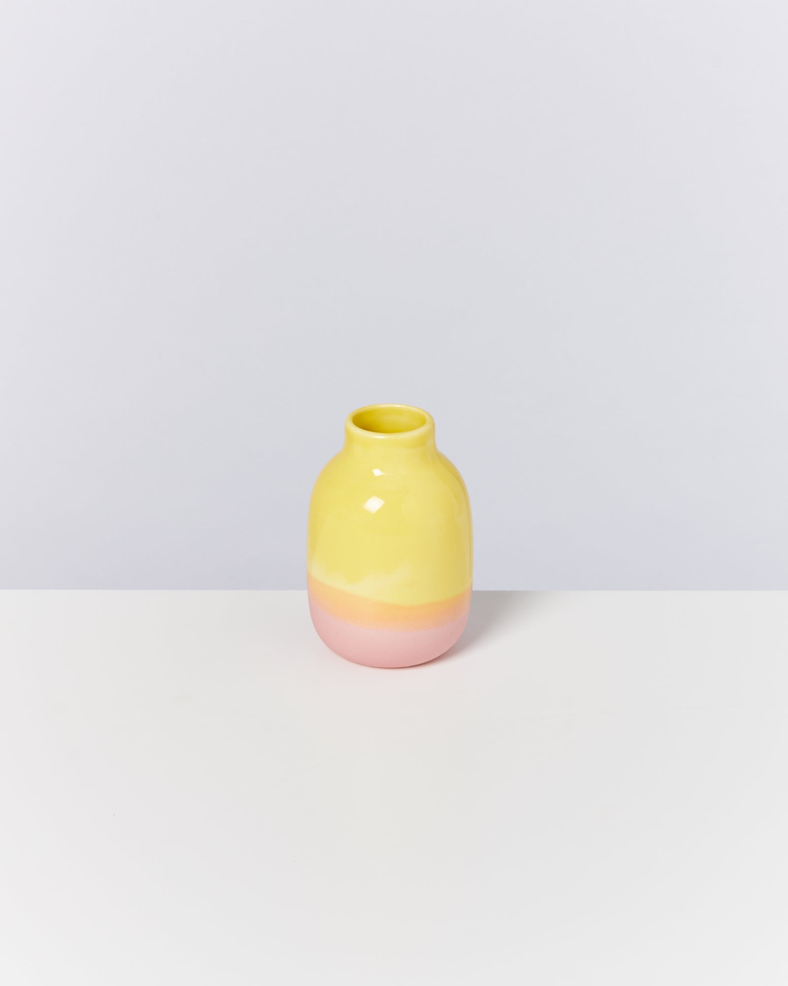 Gelbe und rosa Keramikvase auf weißem Hintergrund, schlichtes und modernes Design.