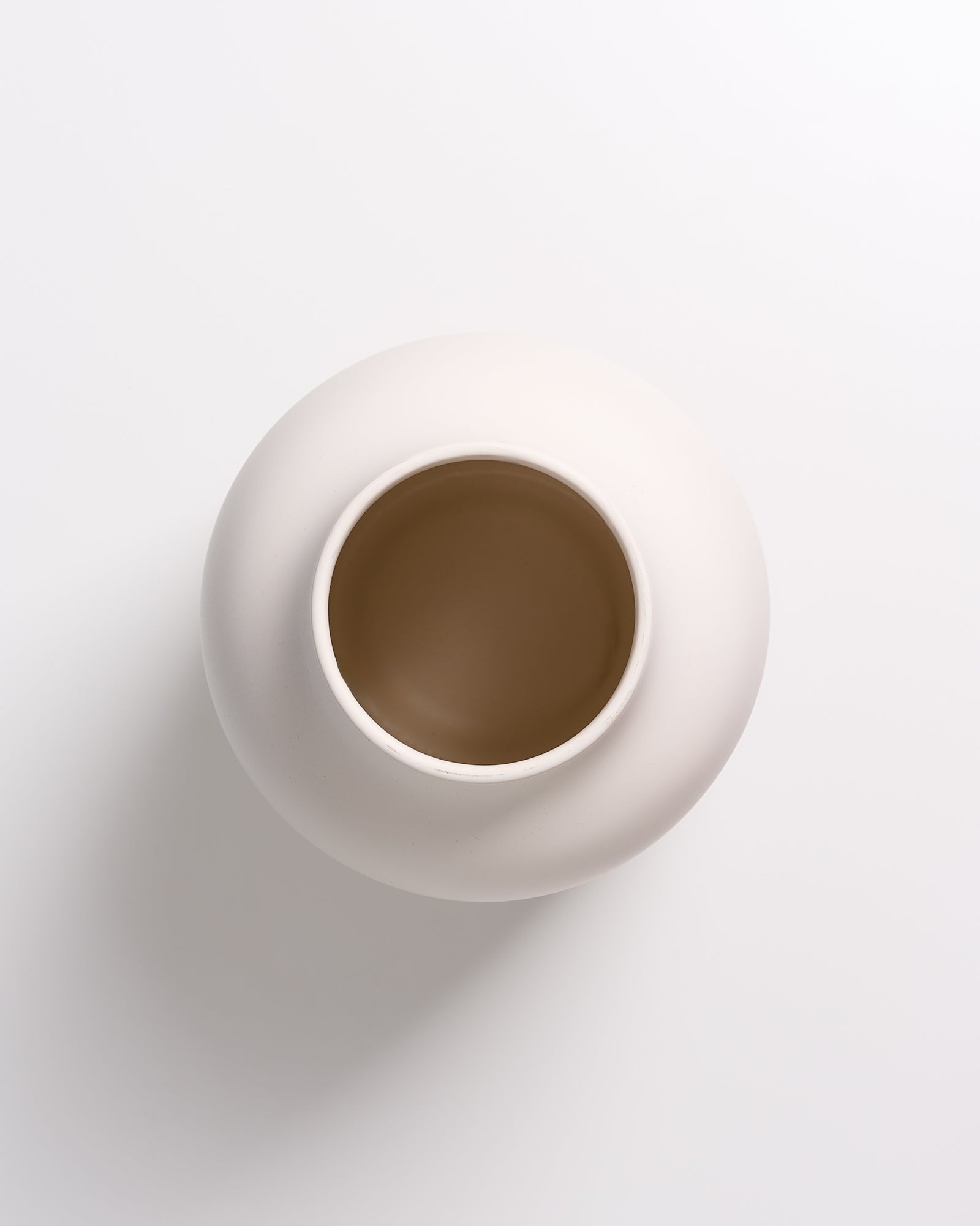 Beige runde Vase aus der Vogelperspektive auf weißem Hintergrund fotografiert.