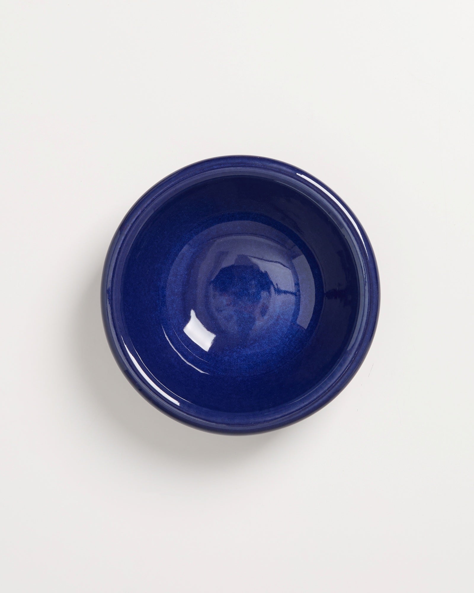 Blaue Keramikschüssel vor weißem Hintergrund, von oben fotografiert.