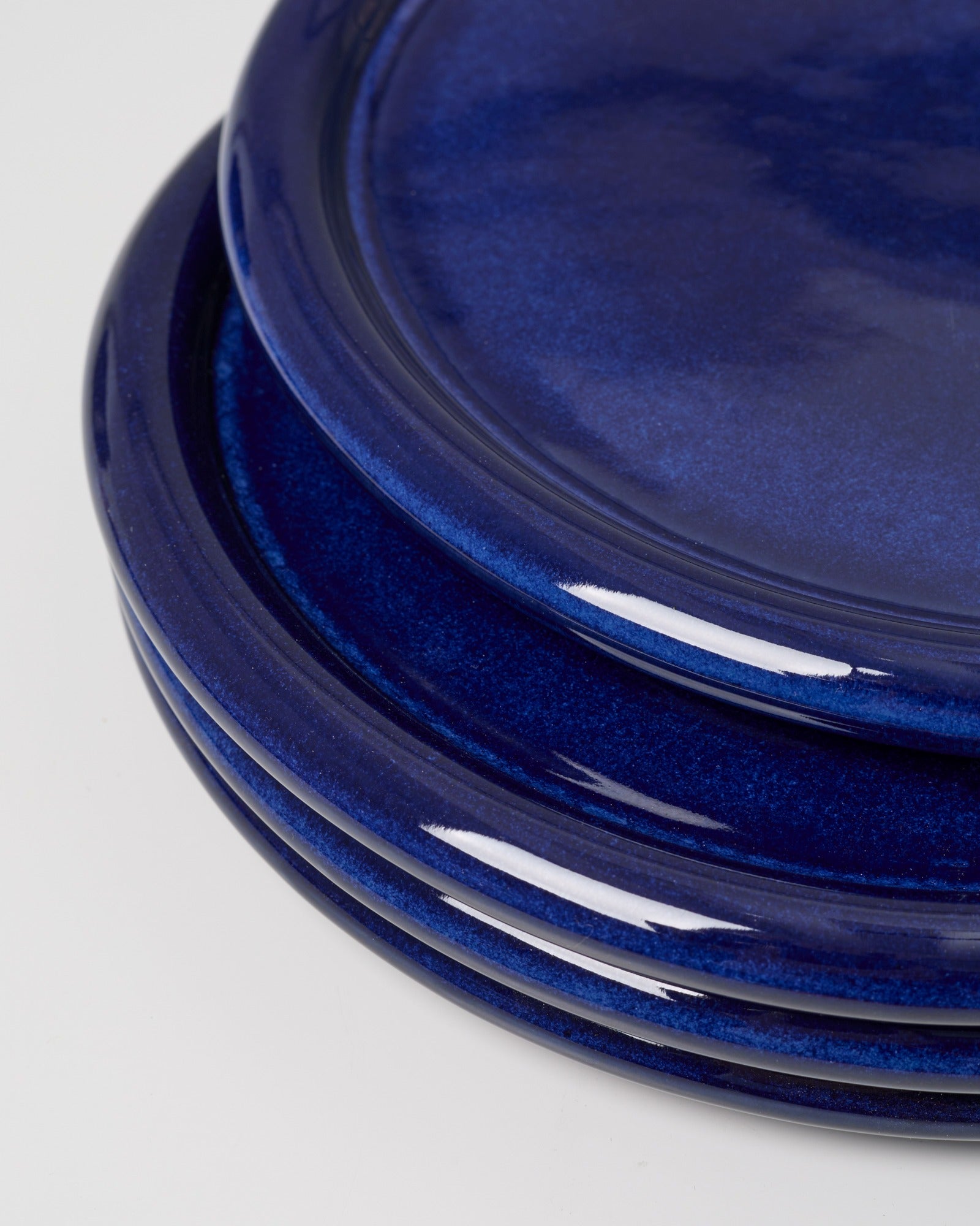 Ein Stapel dunkler blauer Teller auf einem weißen Hintergrund.