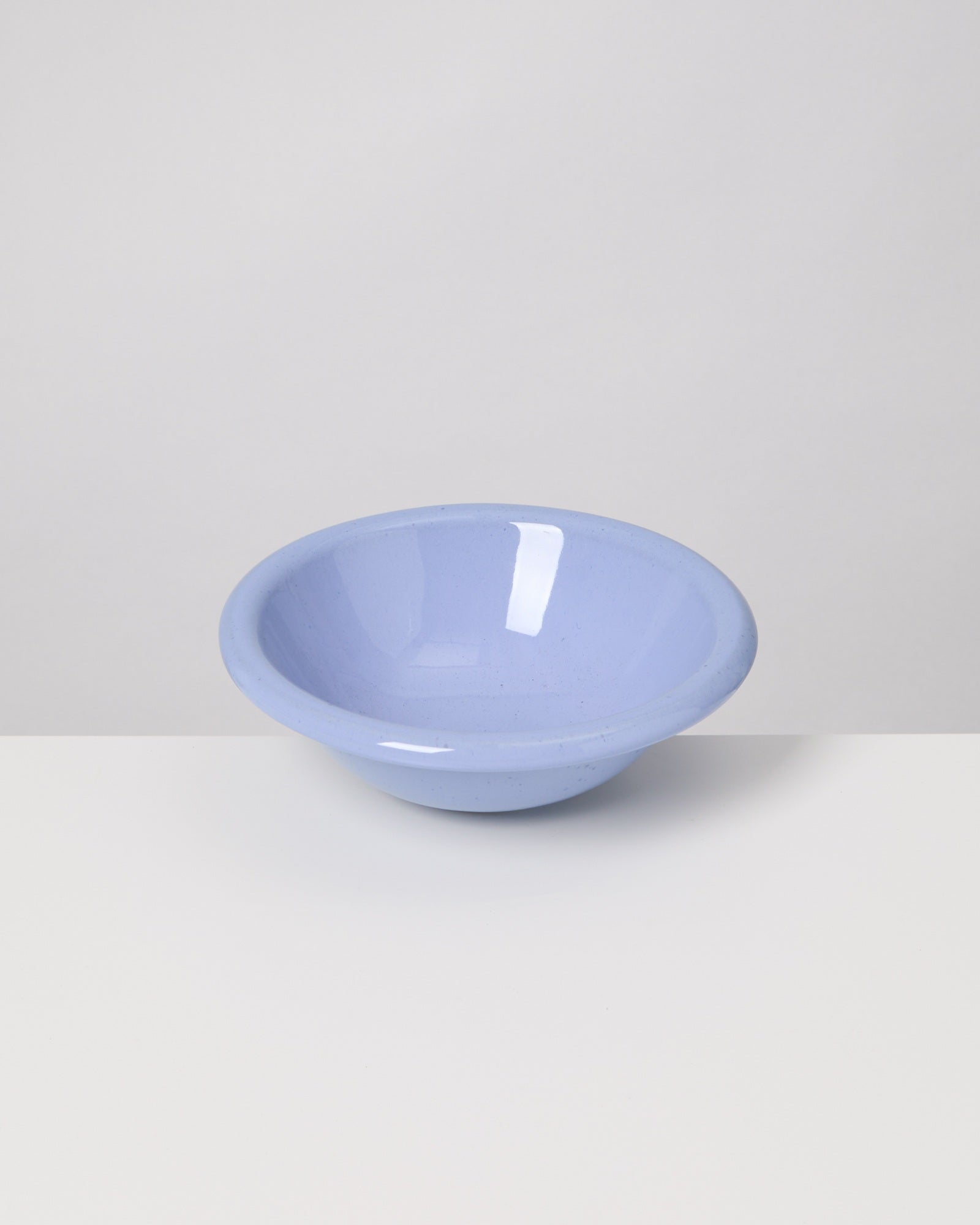 Eine hellblaue Schüssel steht auf einem weißen Tisch vor einem grauen Hintergrund.