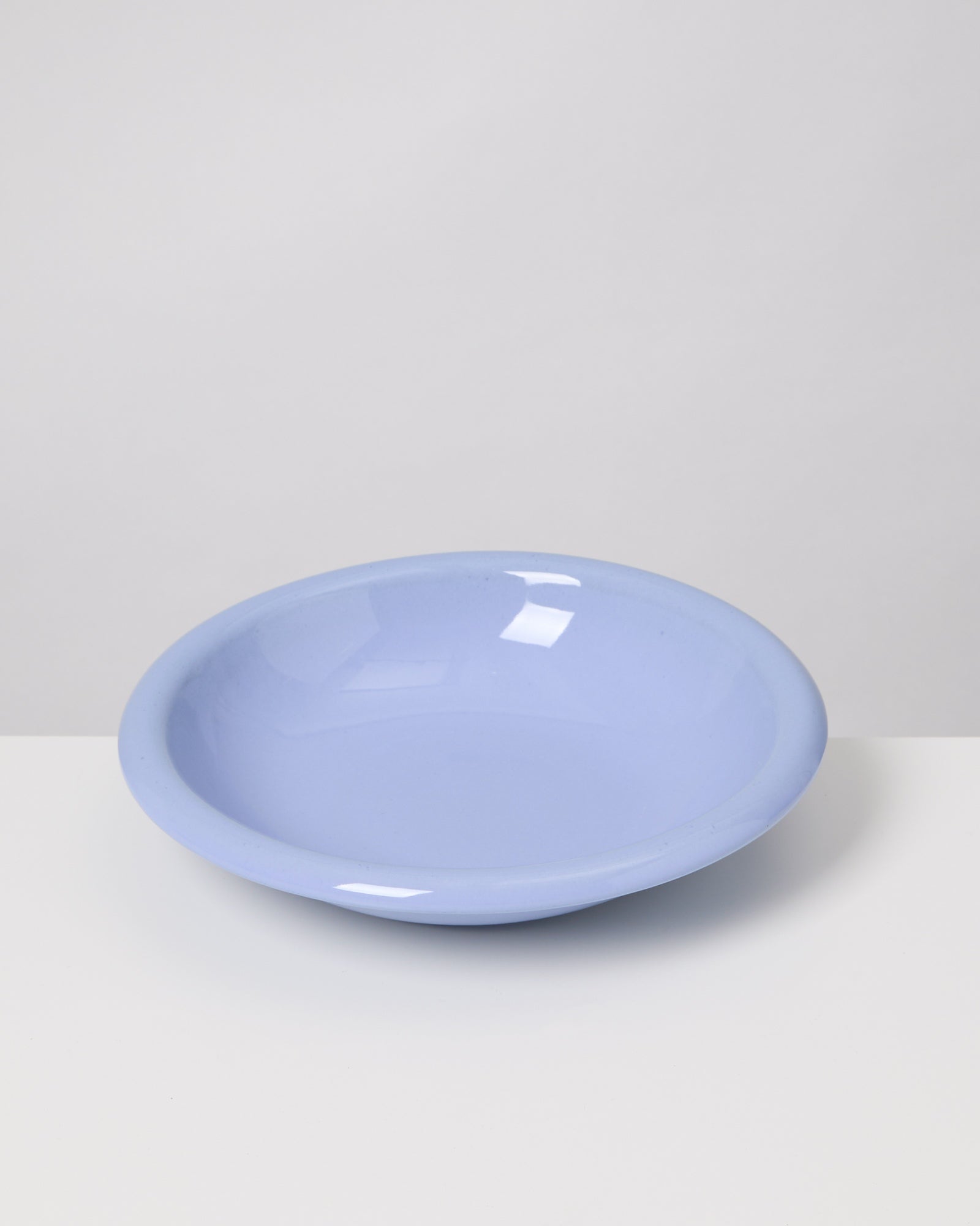 Hellblauer Teller auf weißem Hintergrund, leicht schimmernd.