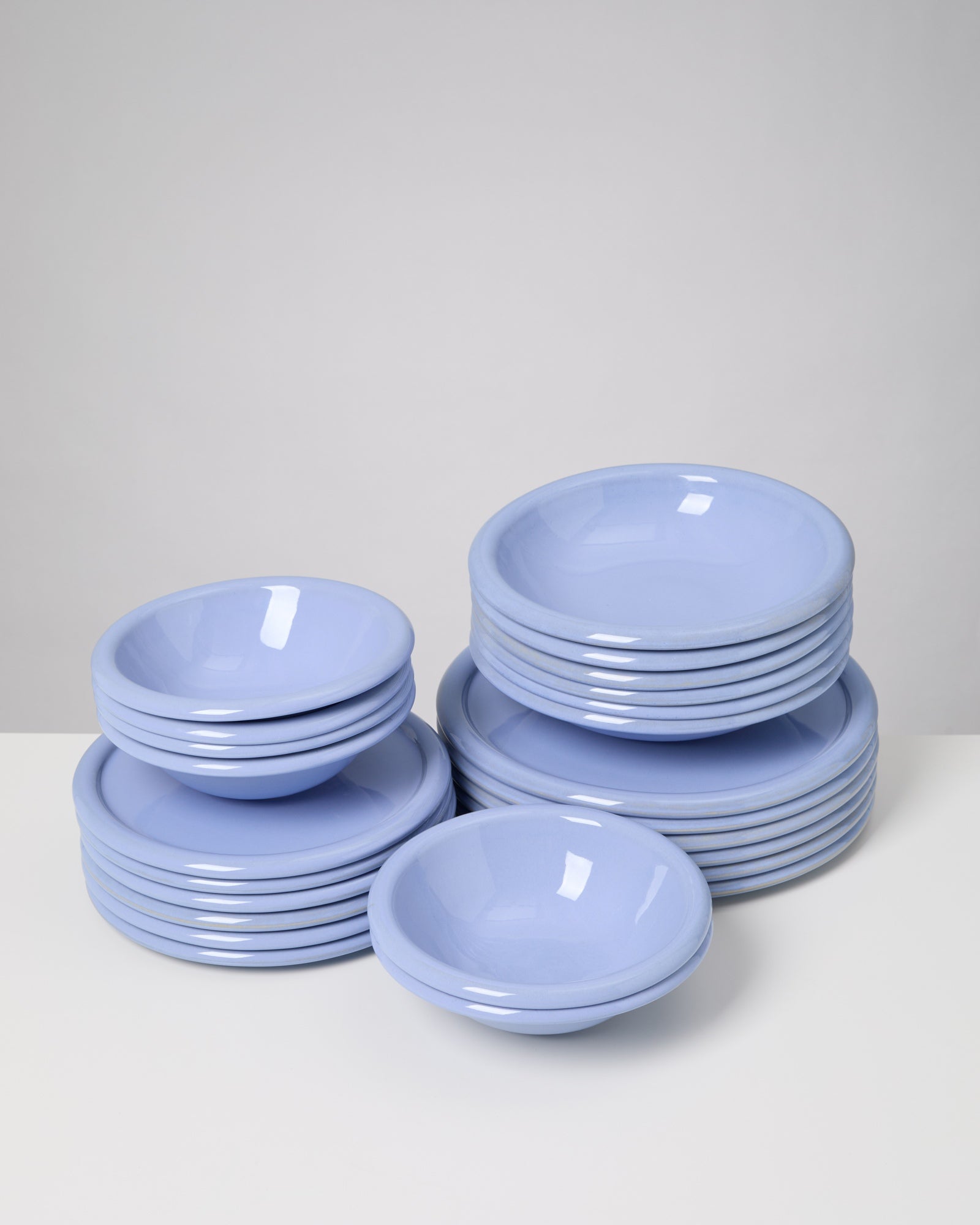 Stapel aus hellblauen Tellern und Schüsseln auf einem weißen Tisch.