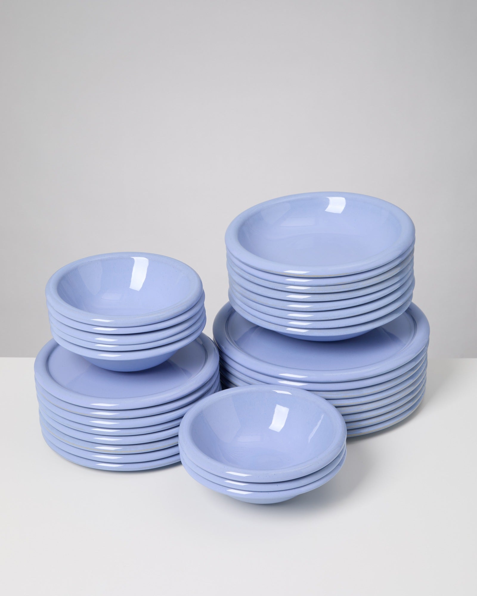 Stapel von hellblauen Tellern und Schüsseln auf einem weißen Tisch.
