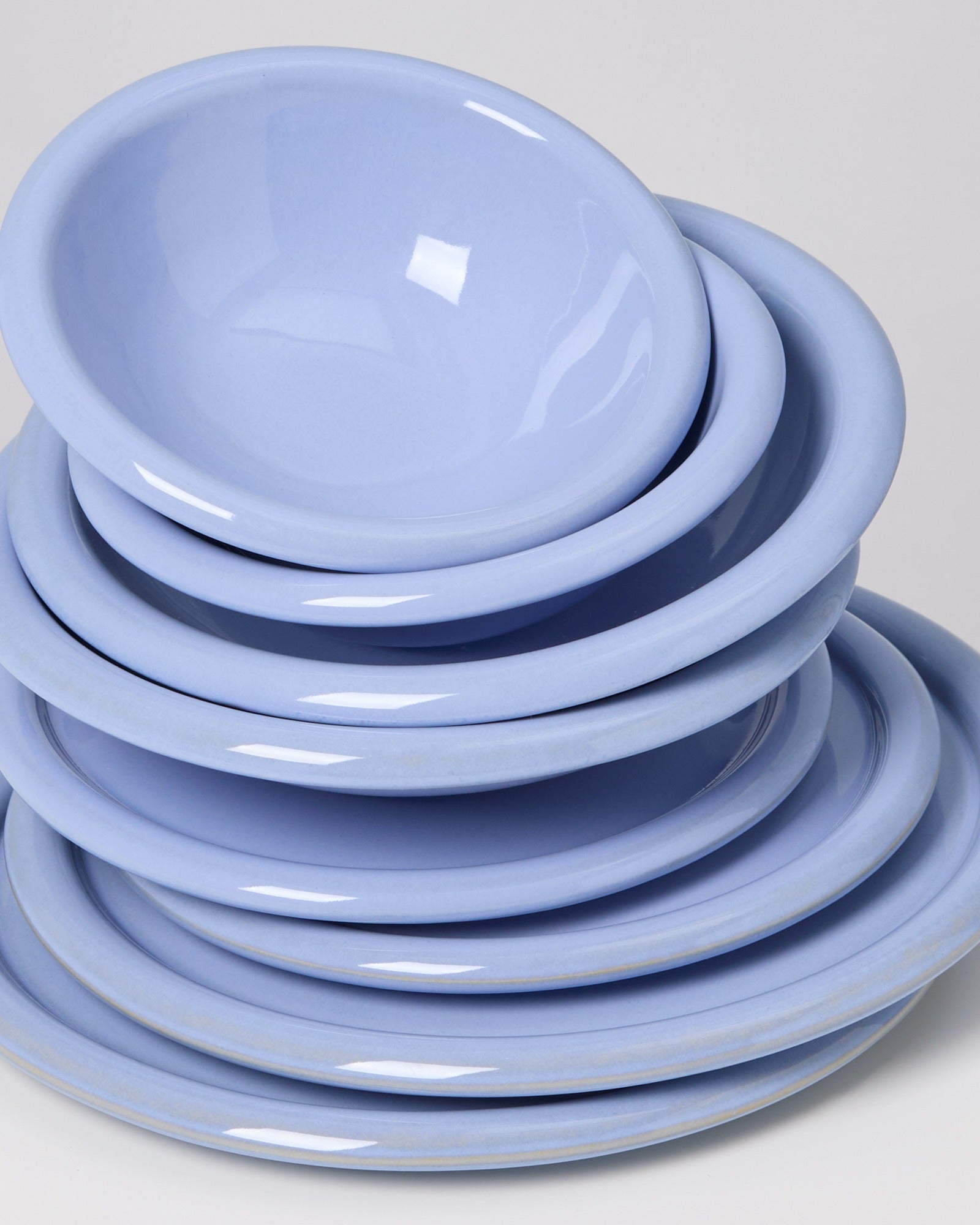 Ein Stapel aus blauen Tellern und Schüsseln vor einem weißen Hintergrund.