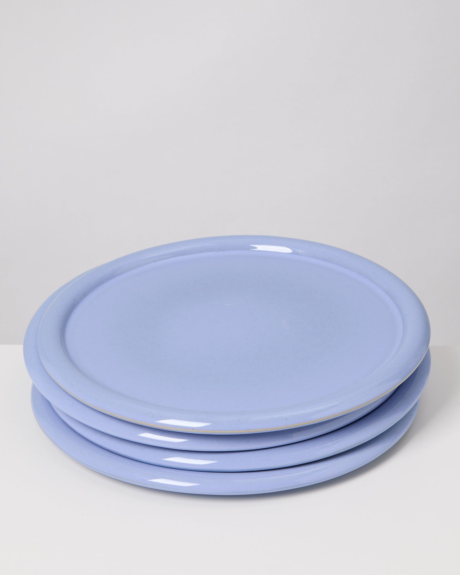 Ein Stapel aus vier hellblauen Tellern auf einer weißen Oberfläche.