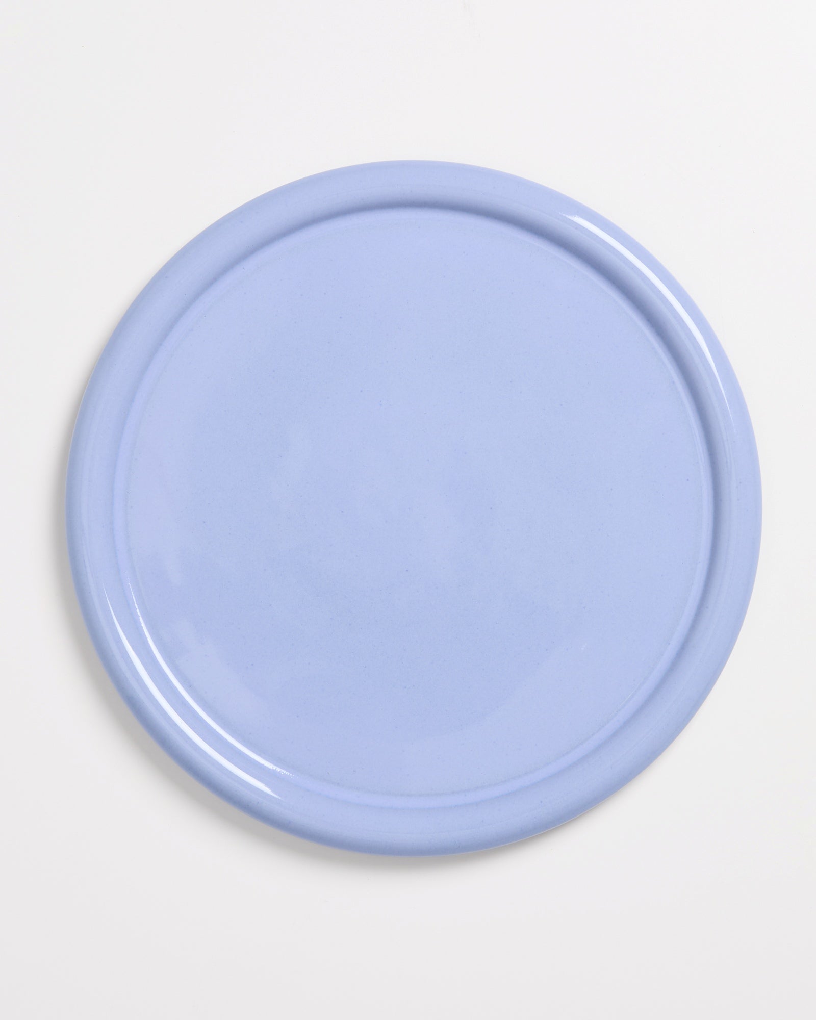 Runder, hellblauer Teller auf weißem Hintergrund.