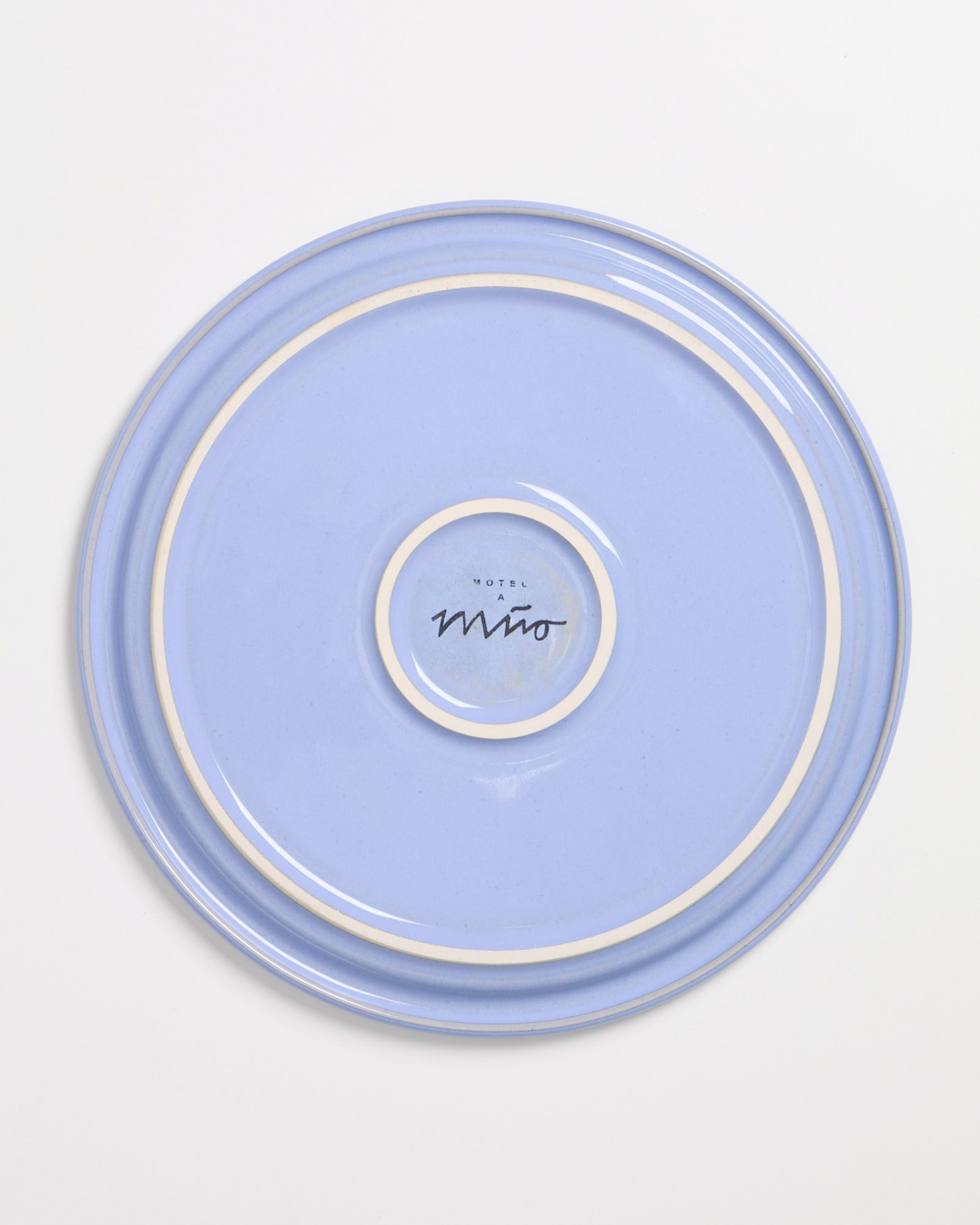 Blauer Teller mit zwei weißen Ringen und einem Logo in der Mitte auf einem weißen Hintergrund.