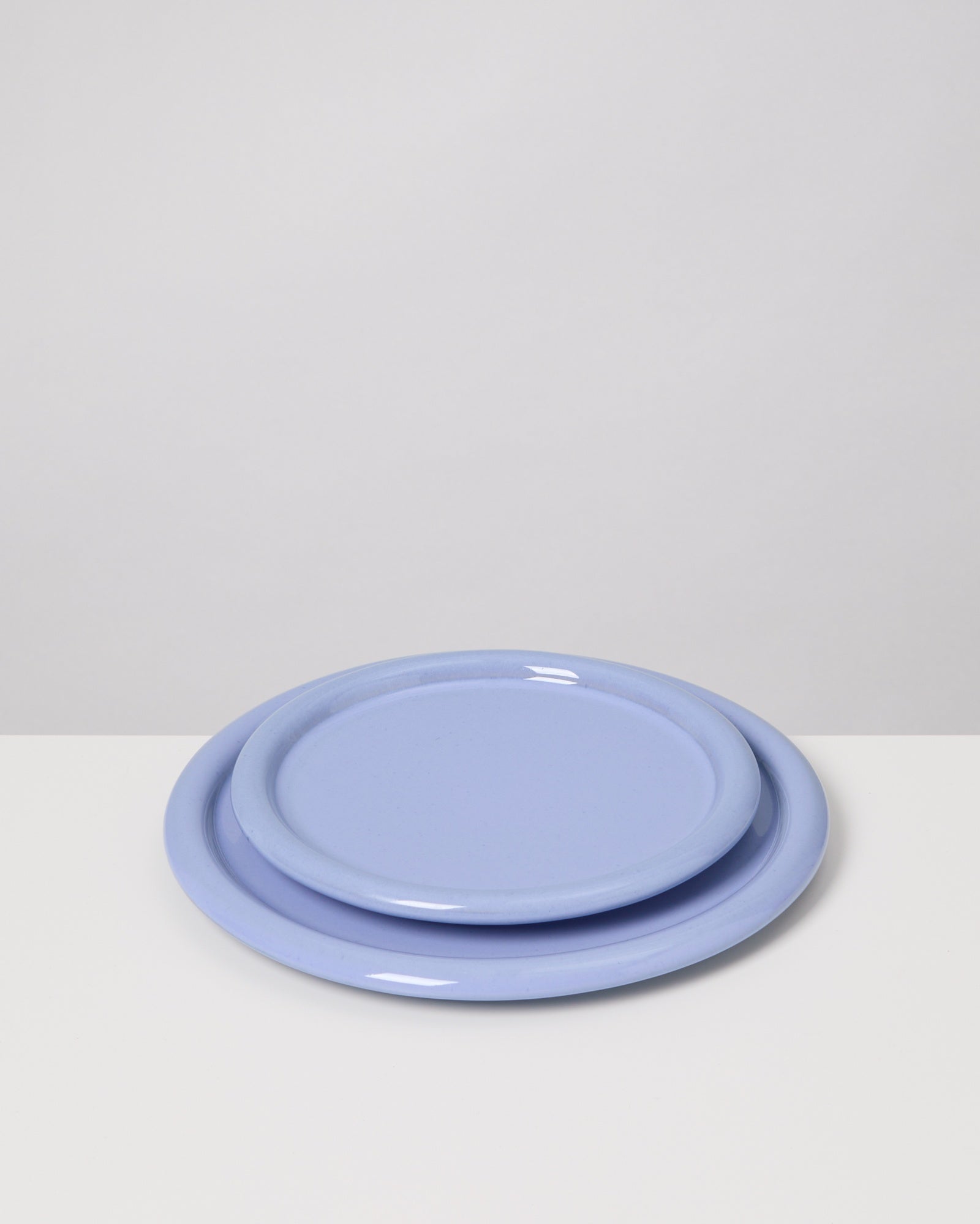 Zwei lavendelfarbene Teller, übereinander gestapelt, auf einem weißen Hintergrund.
