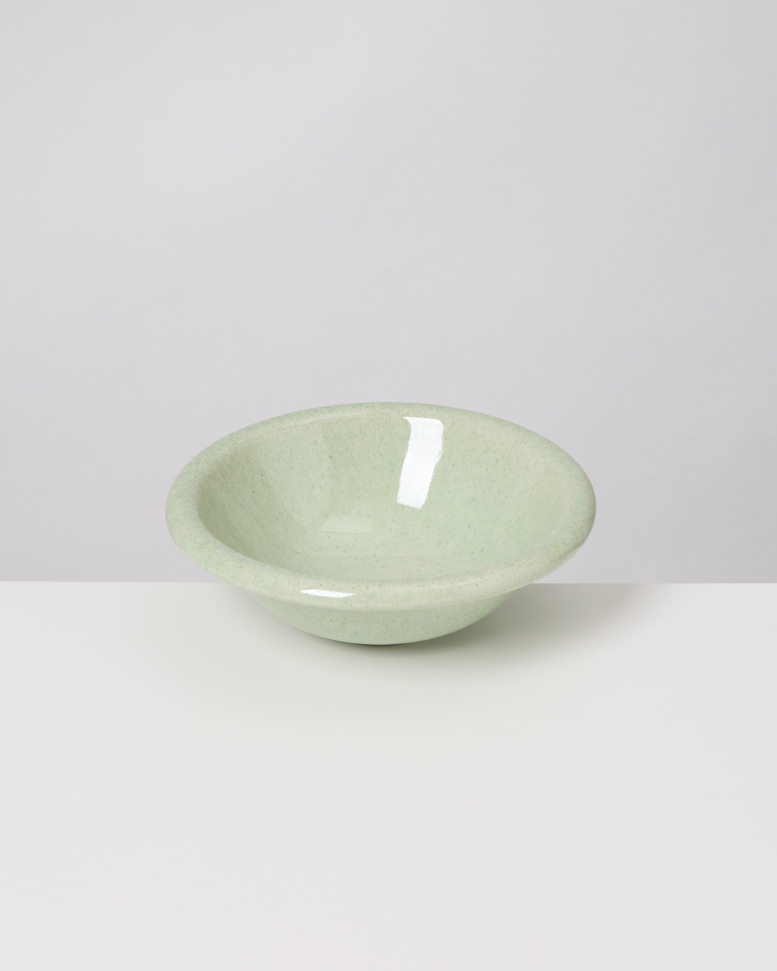 Grüne, glänzende Schale auf einem weißen Hintergrund.