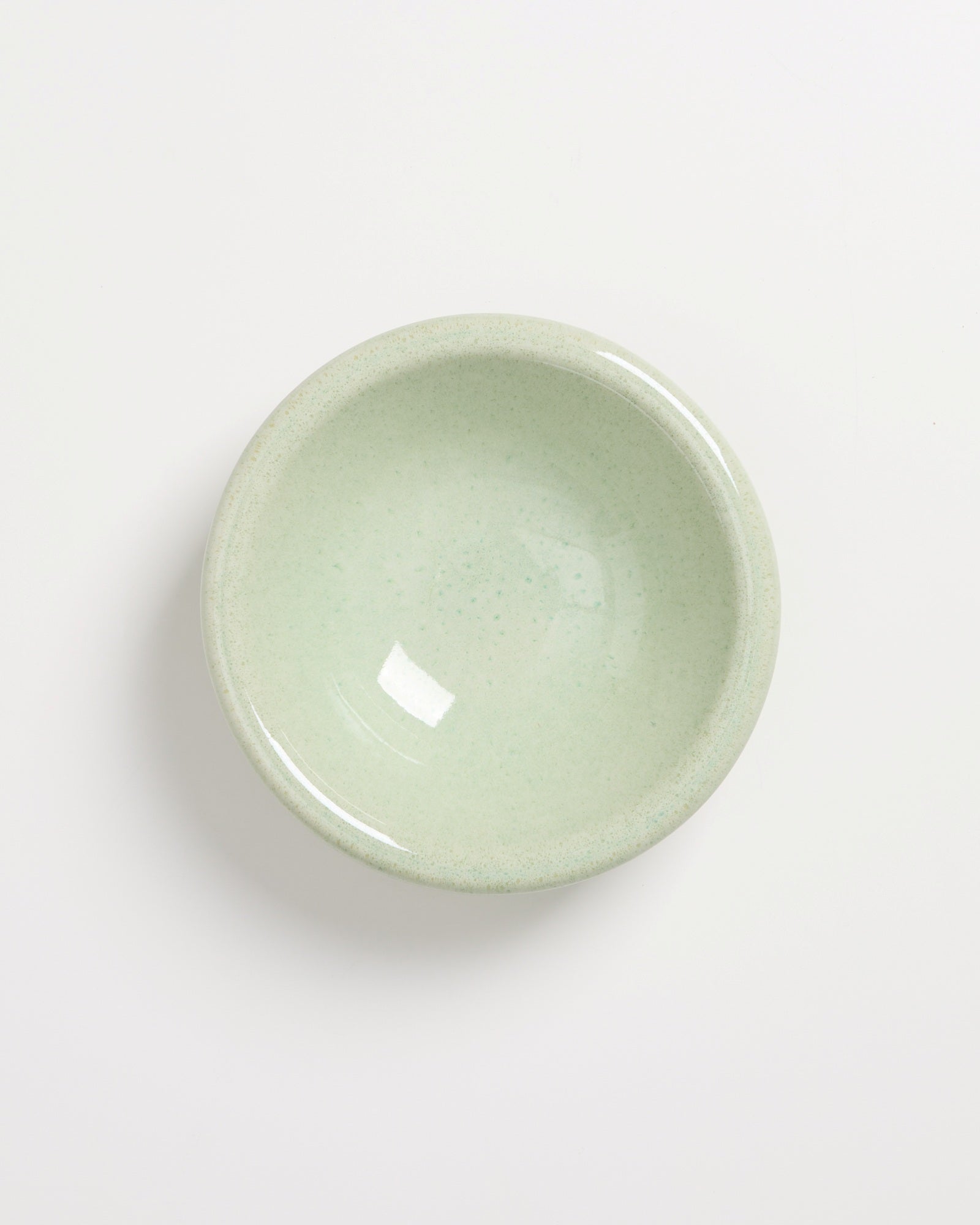 Grüner Keramikteller mit glatter Oberfläche auf weißem Hintergrund.