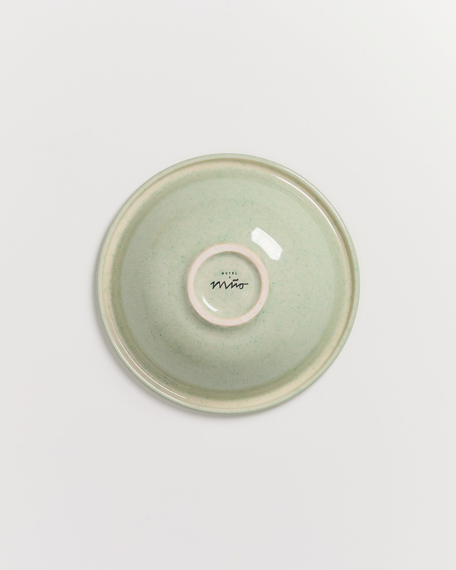 Grüner Keramikteller mit Aufschrift "Hotel Miro" auf der Rückseite, auf weißem Hintergrund.