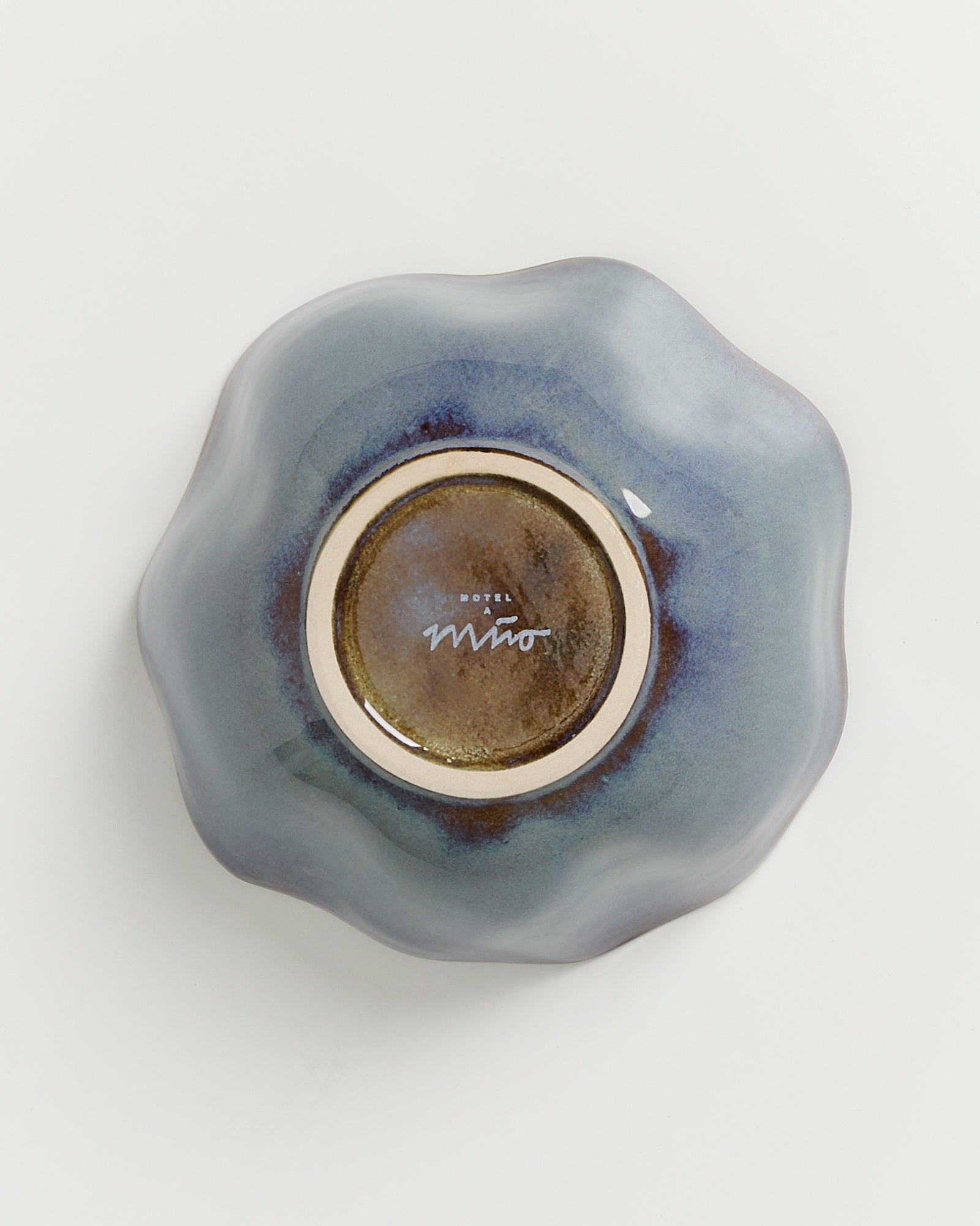 Blau-graue, organisch geformte Keramikschale mit einer glänzenden, unregelmäßigen Oberfläche auf weißem Hintergrund.