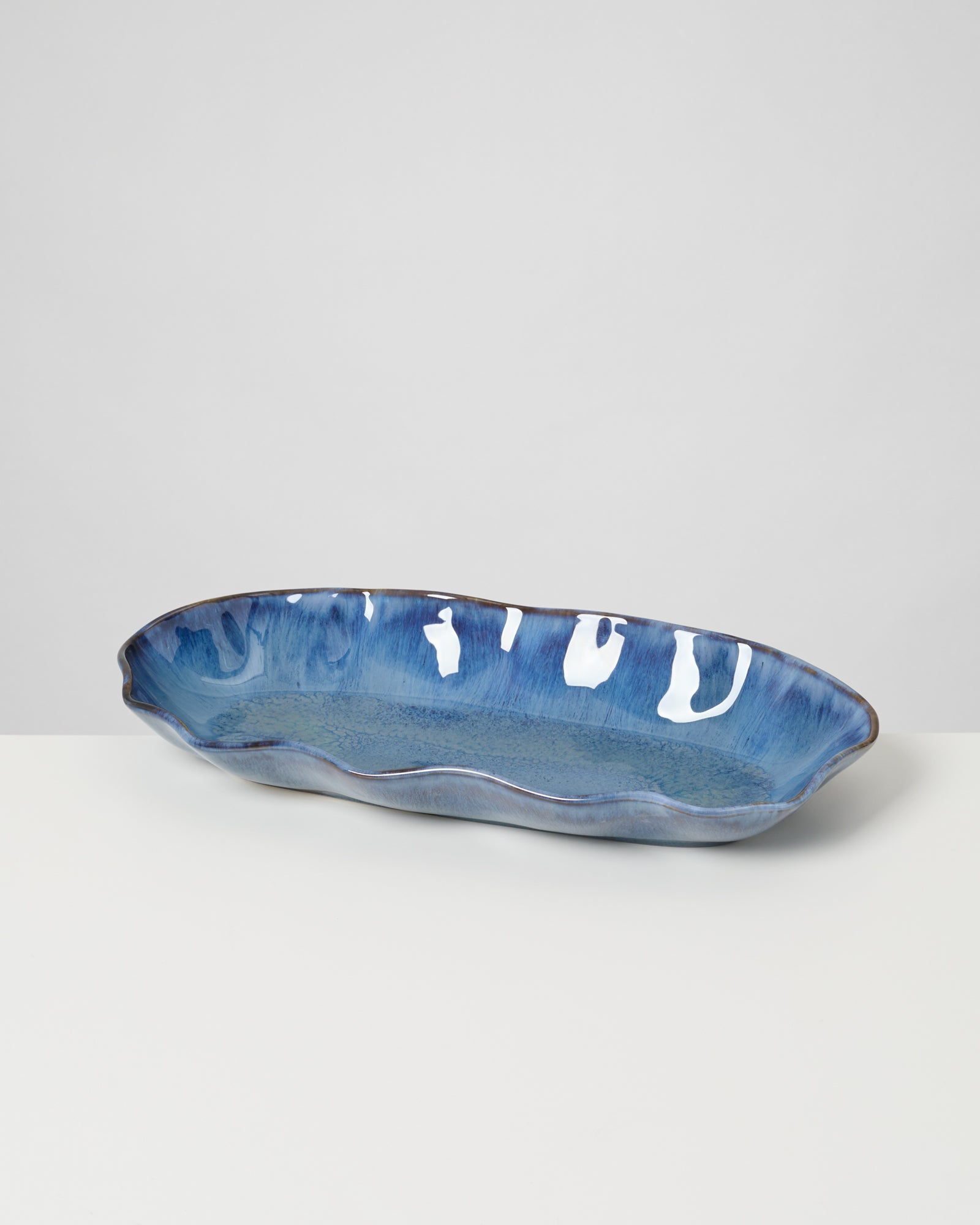Längliche, blaue Keramikschale mit unregelmäßigen weißen Mustern auf einem weißen Hintergrund.