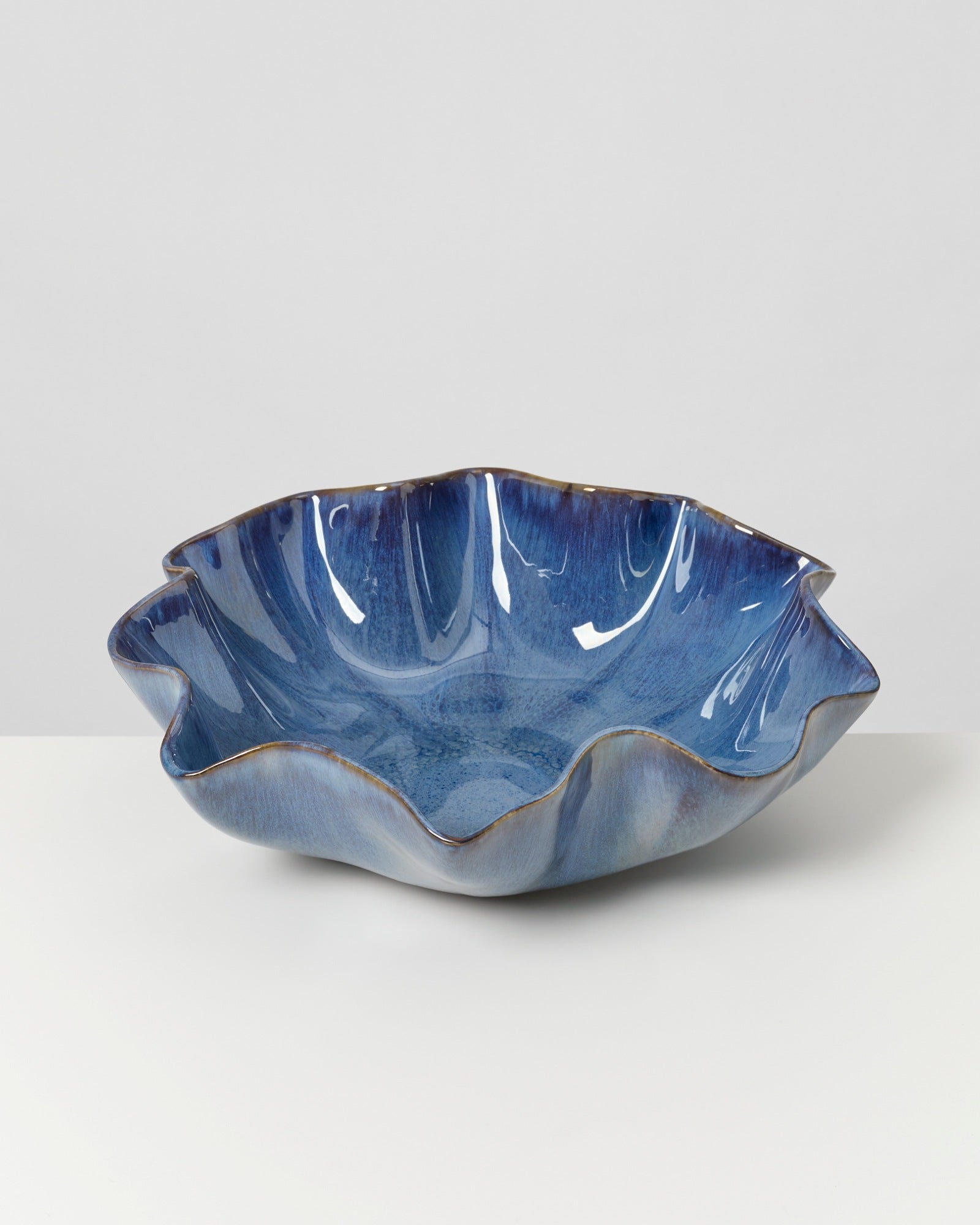Blaue Keramikschüssel mit welligem Rand auf einem weißen Hintergrund.
