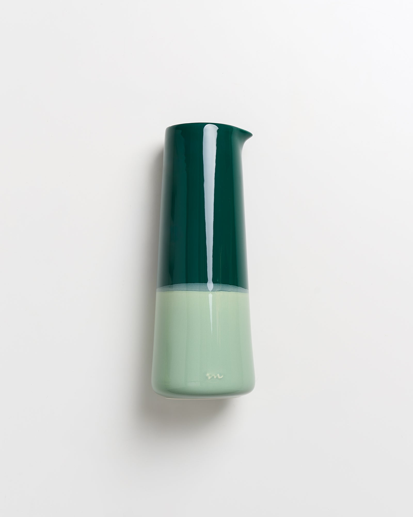 Grüner, zylinderförmiger Krug mit glänzender Oberfläche vor weißem Hintergrund.