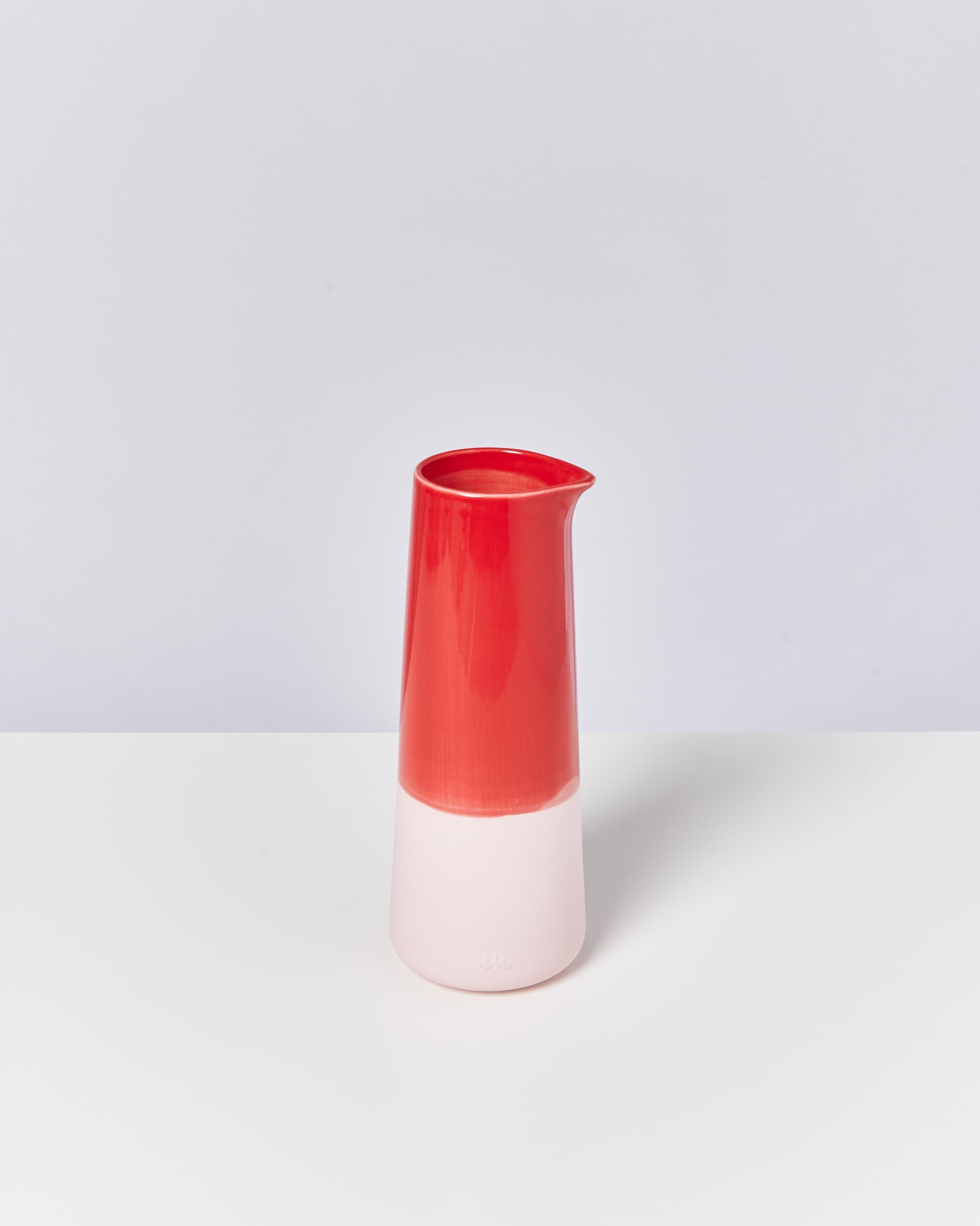 Rote und weiße Vase mit schmalem Hals auf weißem Hintergrund.