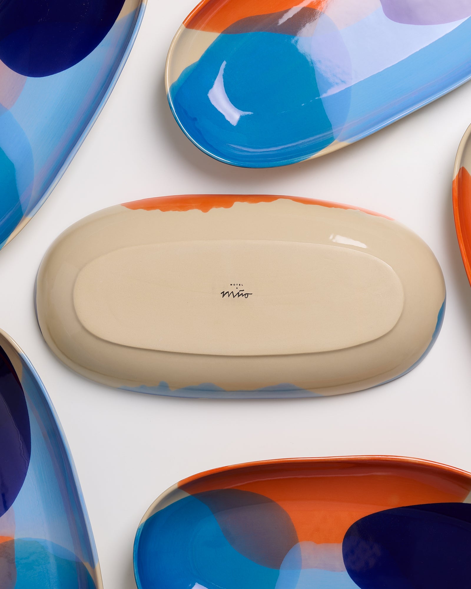 Bunte, ovale Keramikteller mit abstrakten Mustern, einer zeigt die Rückseite mit dem Schriftzug "Hotel Miro".