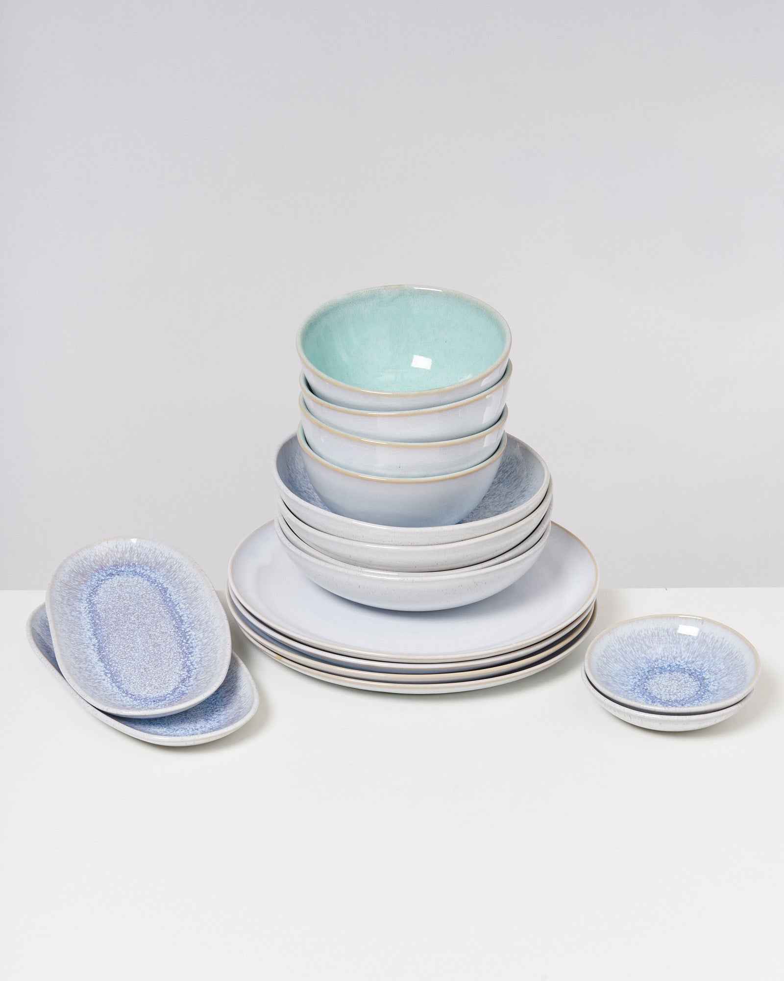 Ein Stapel keramischer Schalen und Teller in verschiedenen blauen und weißen Farbtönen auf einem weißen Tisch.