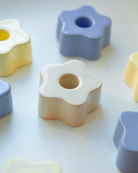 Pastellfarbene, sternförmige Objekte mit Löchern in der Mitte liegen auf einer weißen Oberfläche.