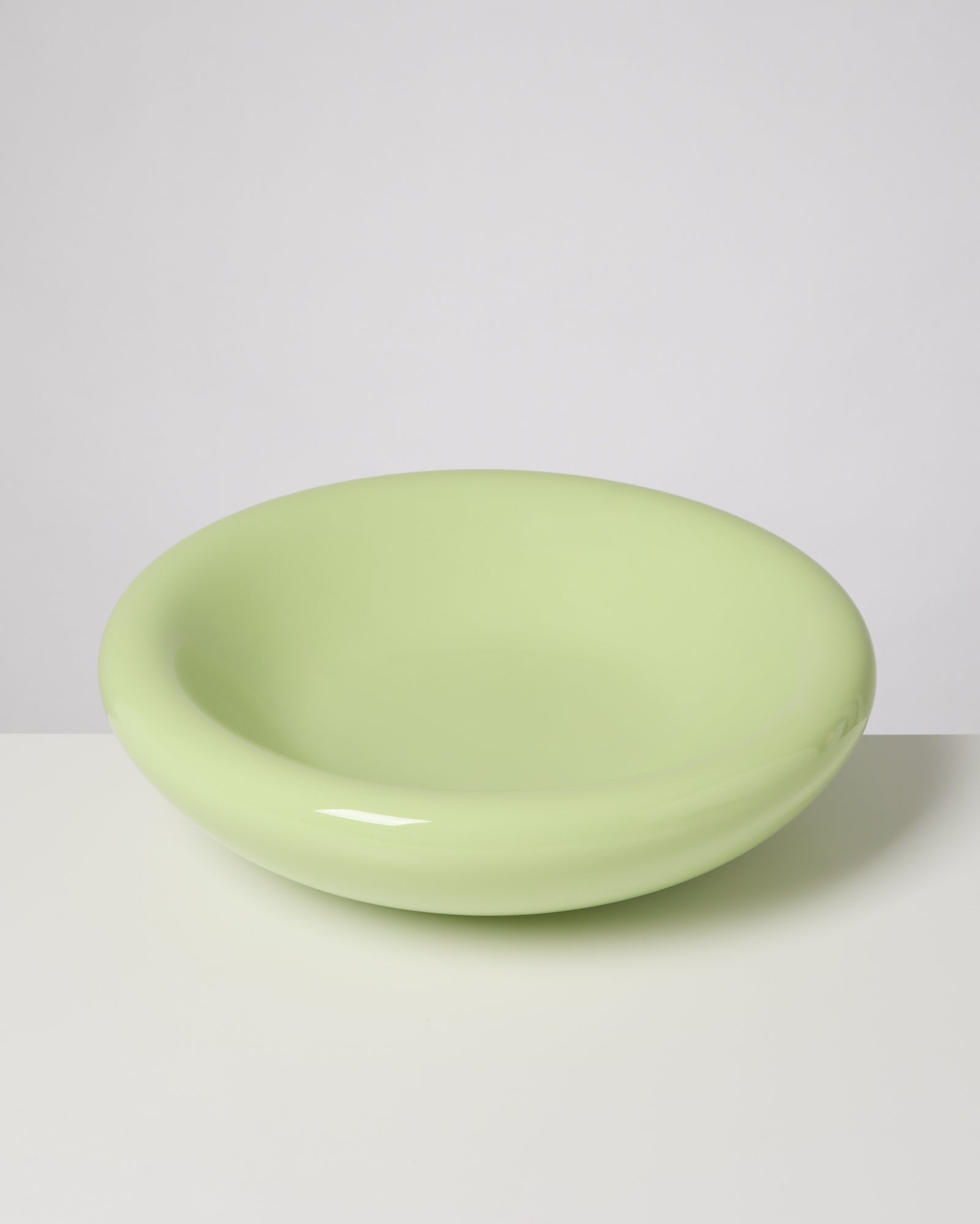 Grüne, runde Schüssel mit glatter Oberfläche auf weißem Hintergrund.