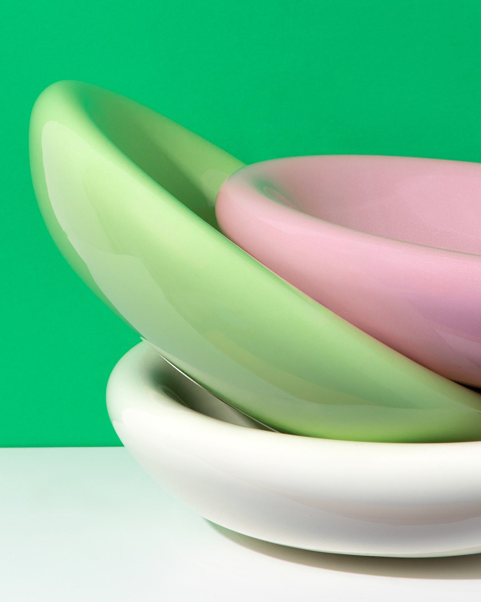 Drei bunte, ineinander gestapelte Schüsseln vor einem grünen Hintergrund.