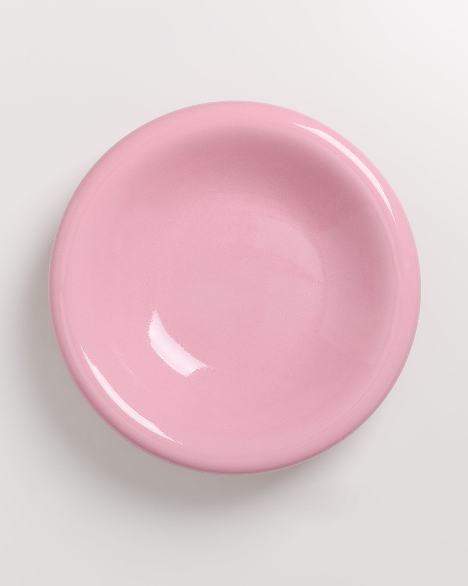 Runder, rosafarbener Teller auf einem weißen Hintergrund.