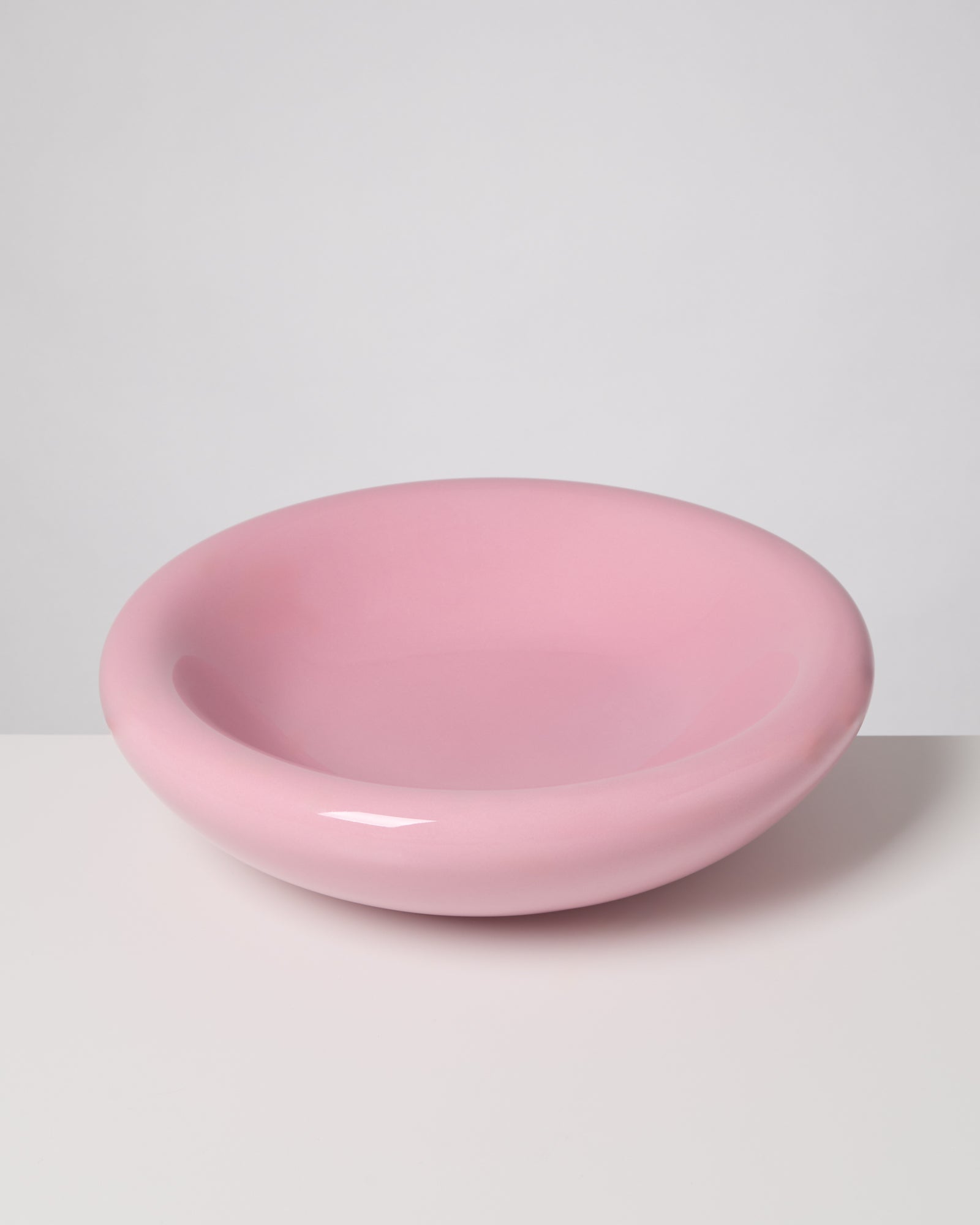 Rosa, runde Keramikschüssel auf weißem Untergrund vor grauem Hintergrund.