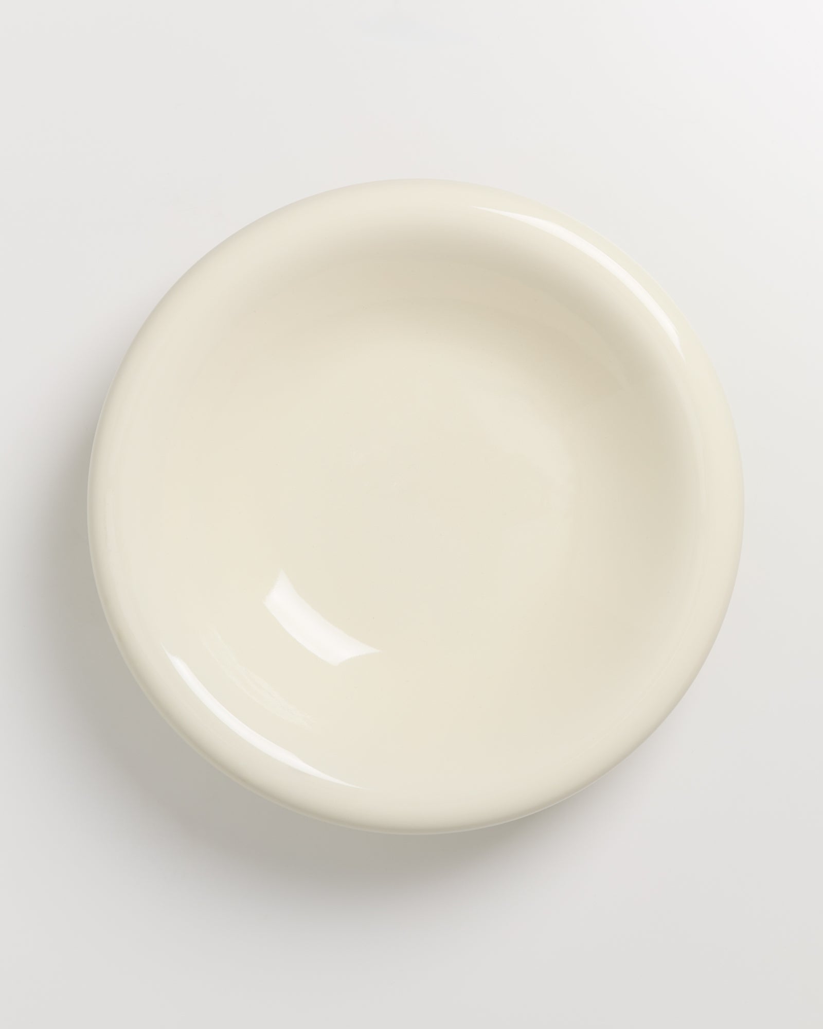 Ein leerer, beigefarbener Teller auf einem weißen Hintergrund.