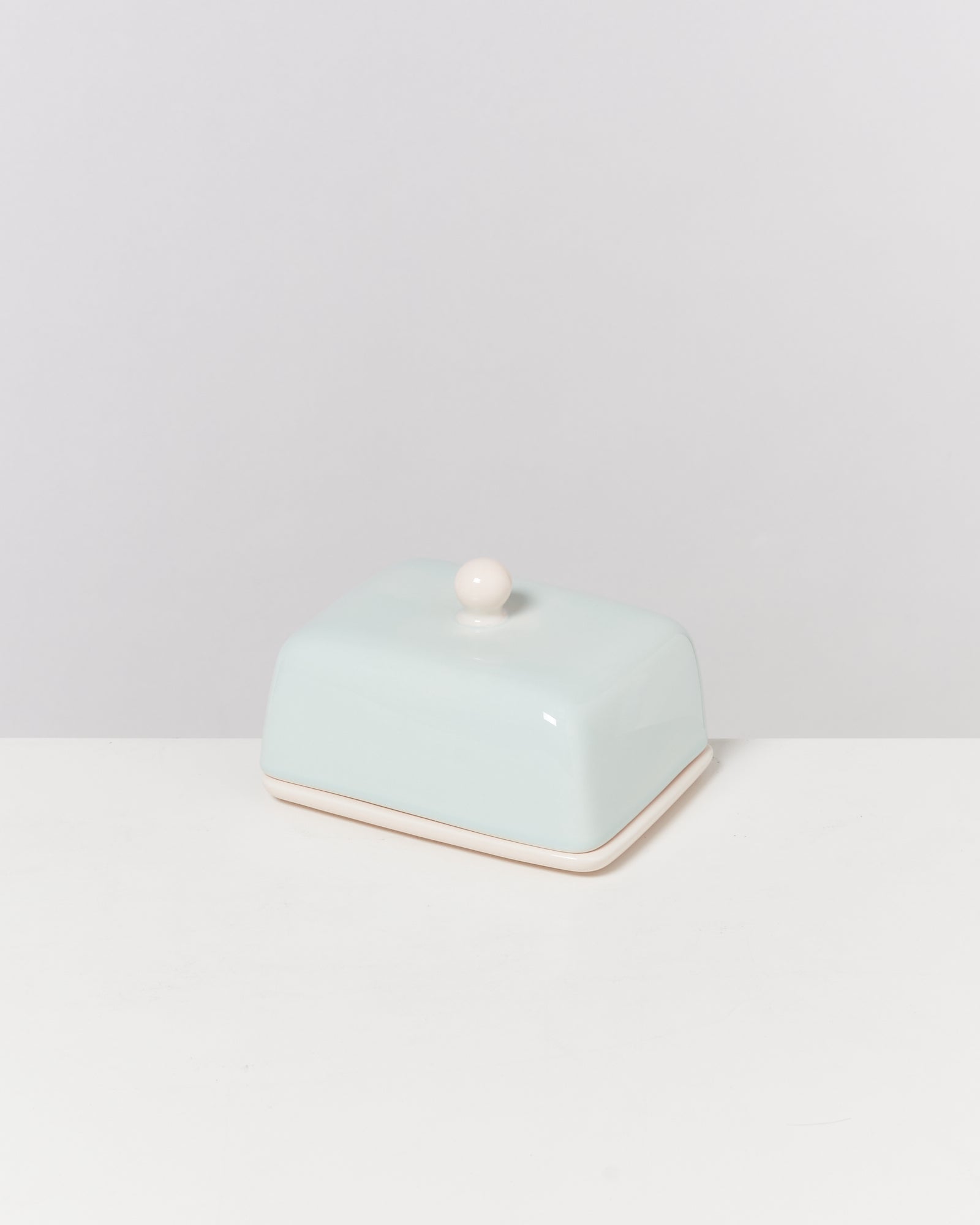 Hellblaue Butterdose mit Knauf auf weißem Hintergrund.