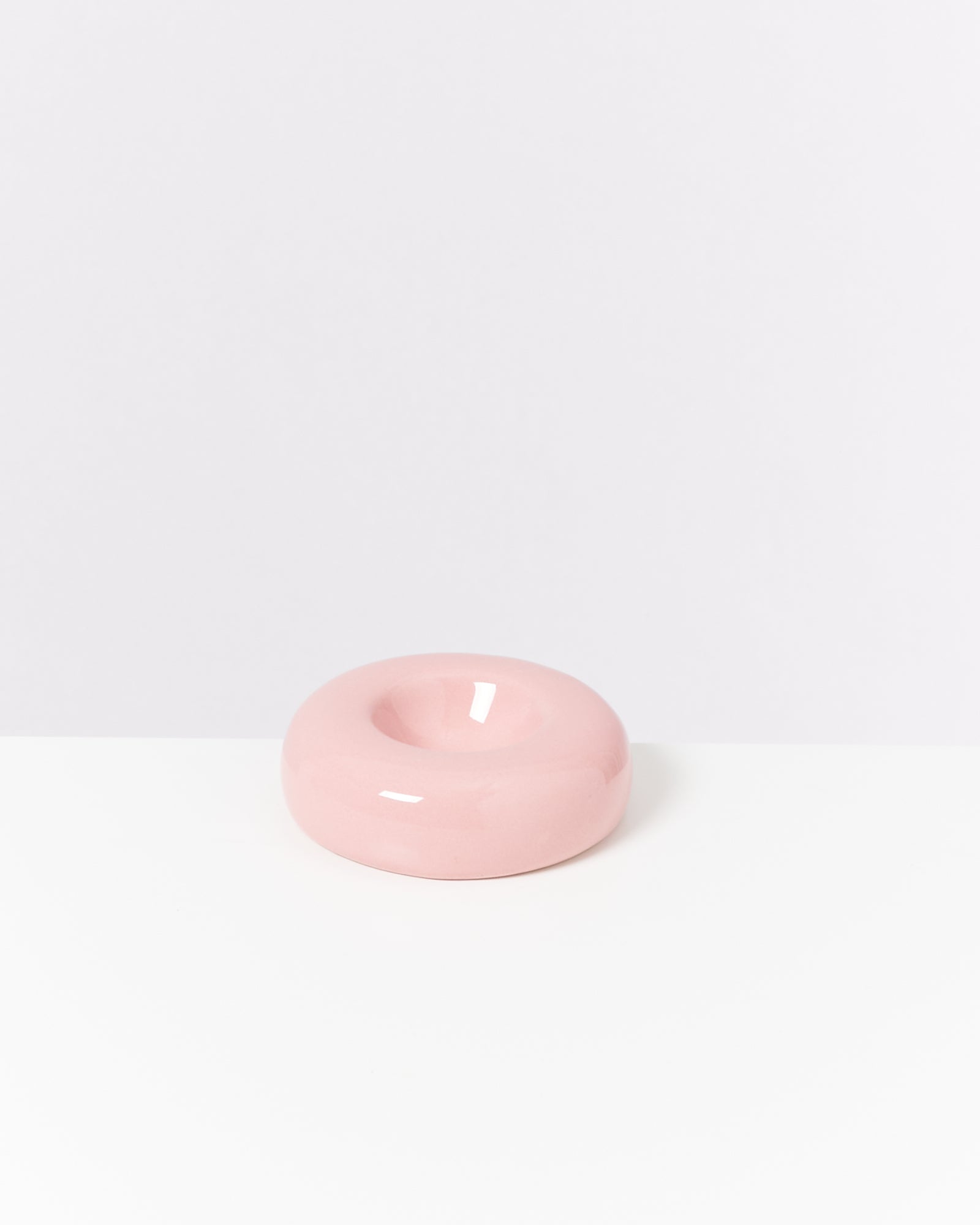 Rosa, ringförmige Keramikskulptur auf weißem Hintergrund.