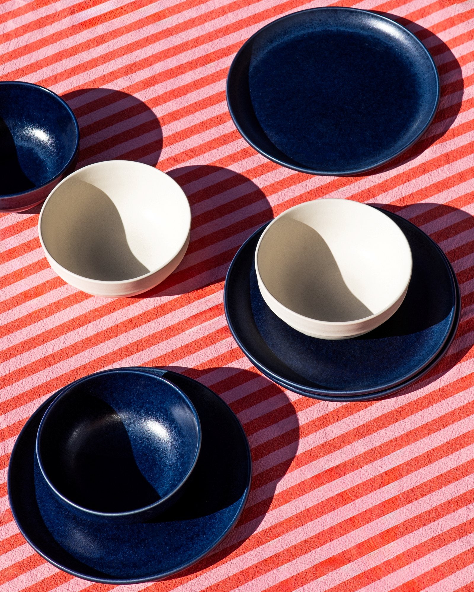 Verschiedene Schalen und Teller auf rot-weiß gestreifter Tischdecke arrangiert.