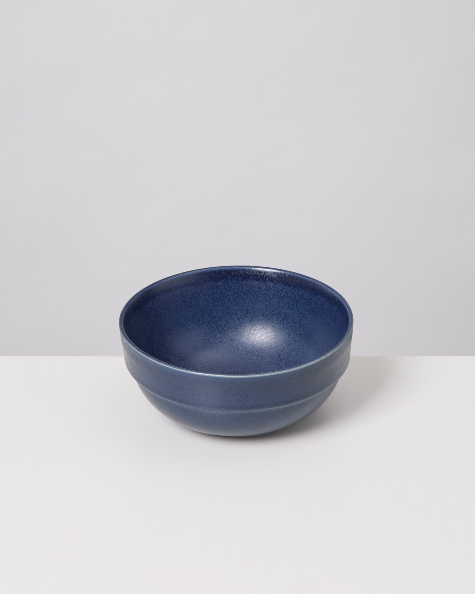 Dunkelblaue, runde Keramikschüssel auf einem weißen Hintergrund.