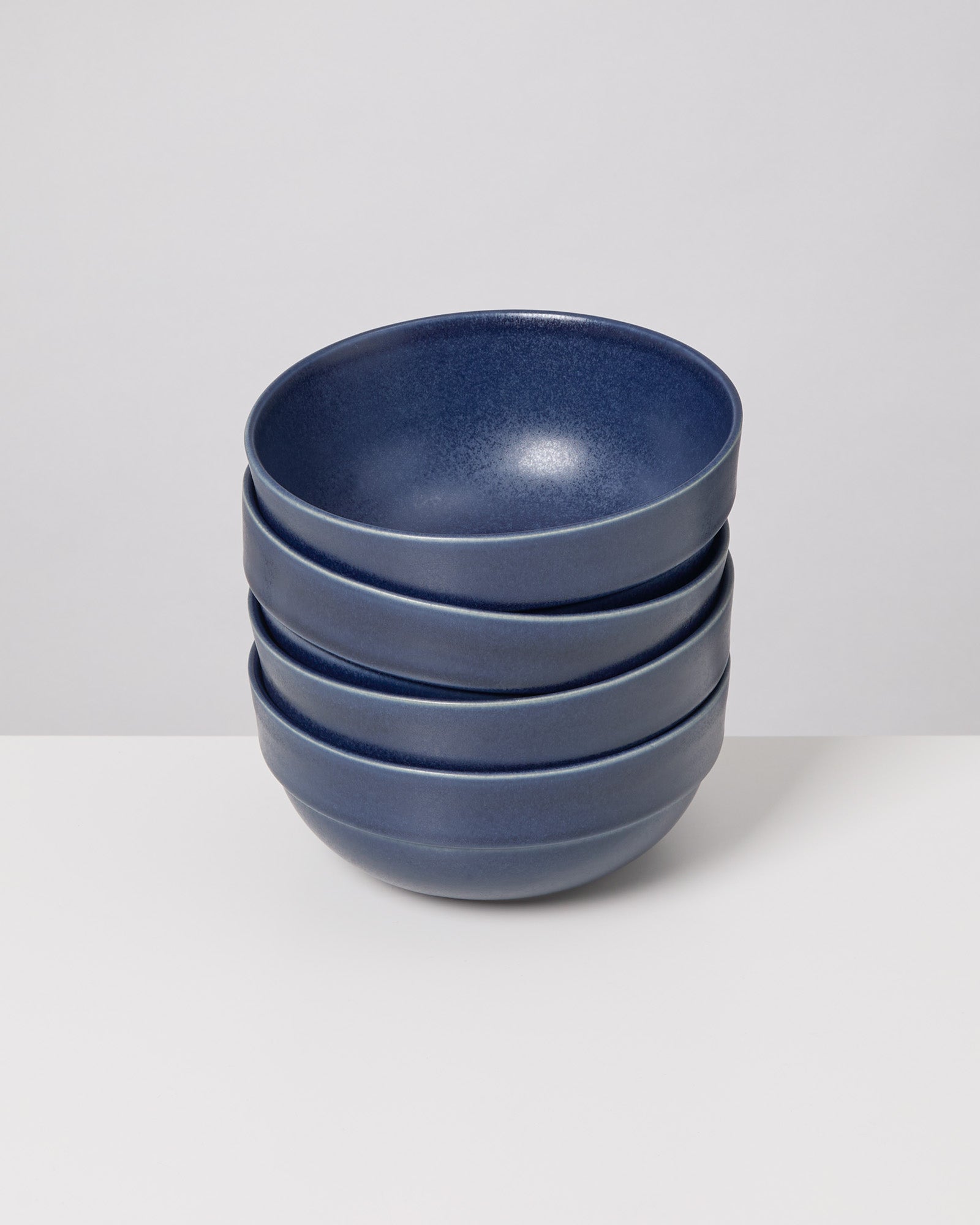 Ein Stapel von vier blauen Schalen steht auf einem weißen Hintergrund.