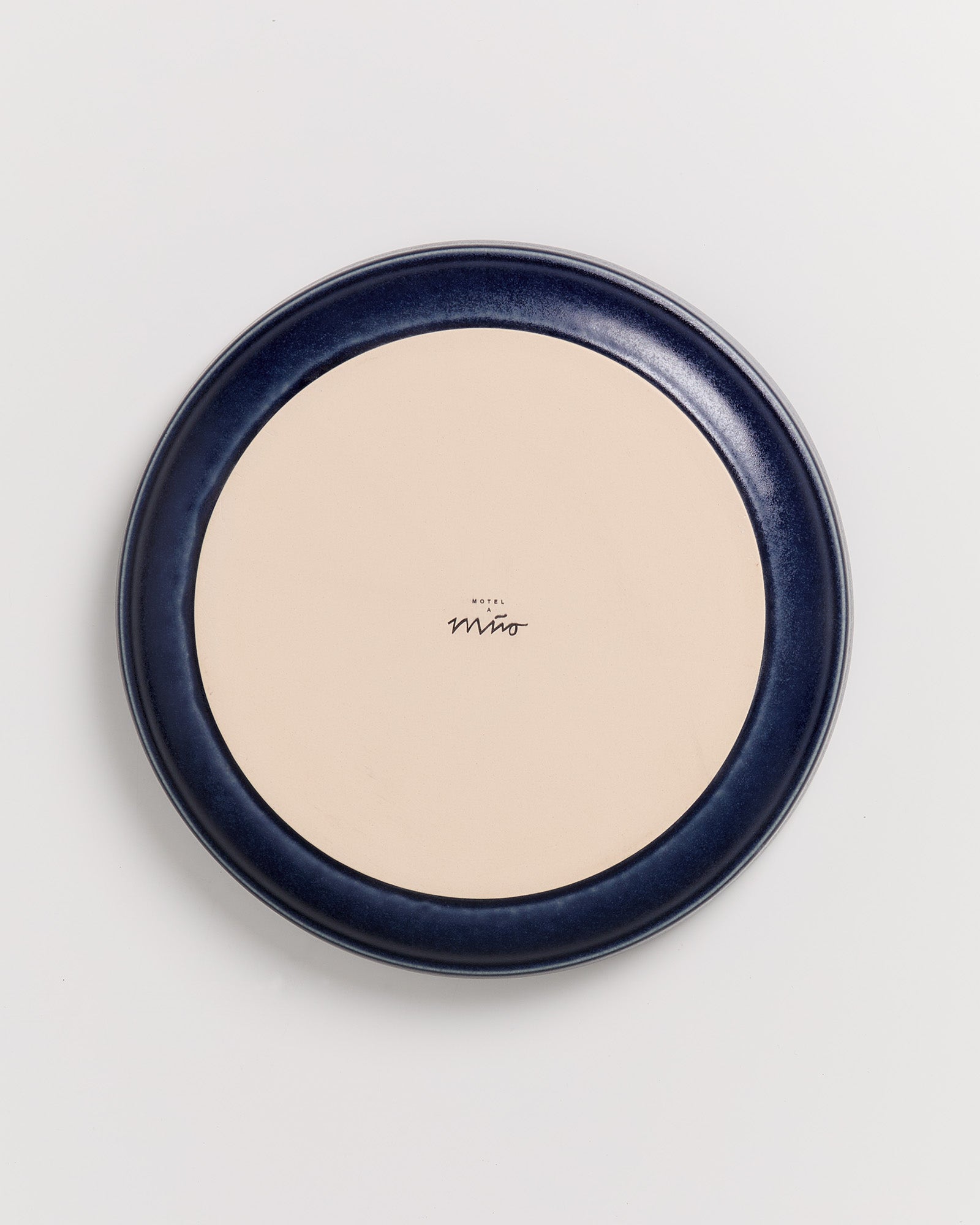 Runder Teller mit blauem Rand und cremefarbenem Zentrum auf weißem Hintergrund, beschriftet mit "Hotel Miro".