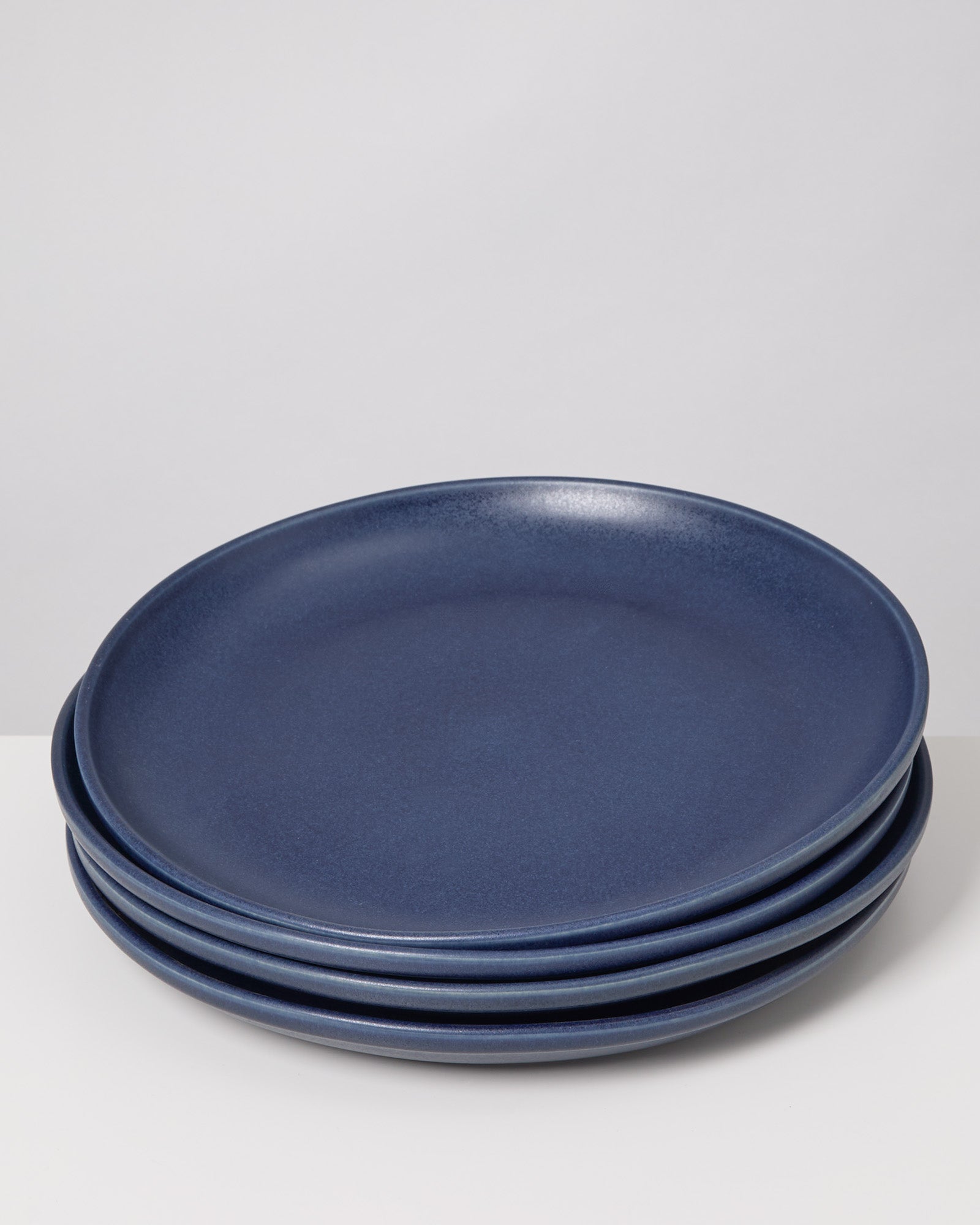 Vier dunkelblaue Teller sind übereinander gestapelt.
