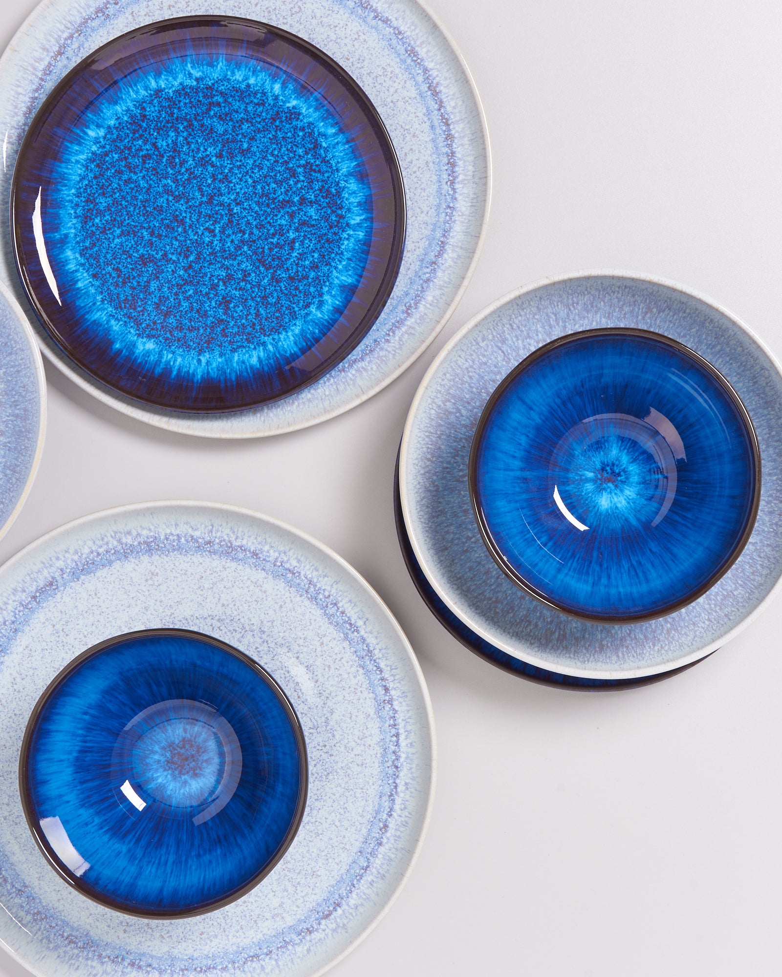 Mehrere blaue Keramikteller mit einem strahlenartigen Muster auf einer weißen Oberfläche.