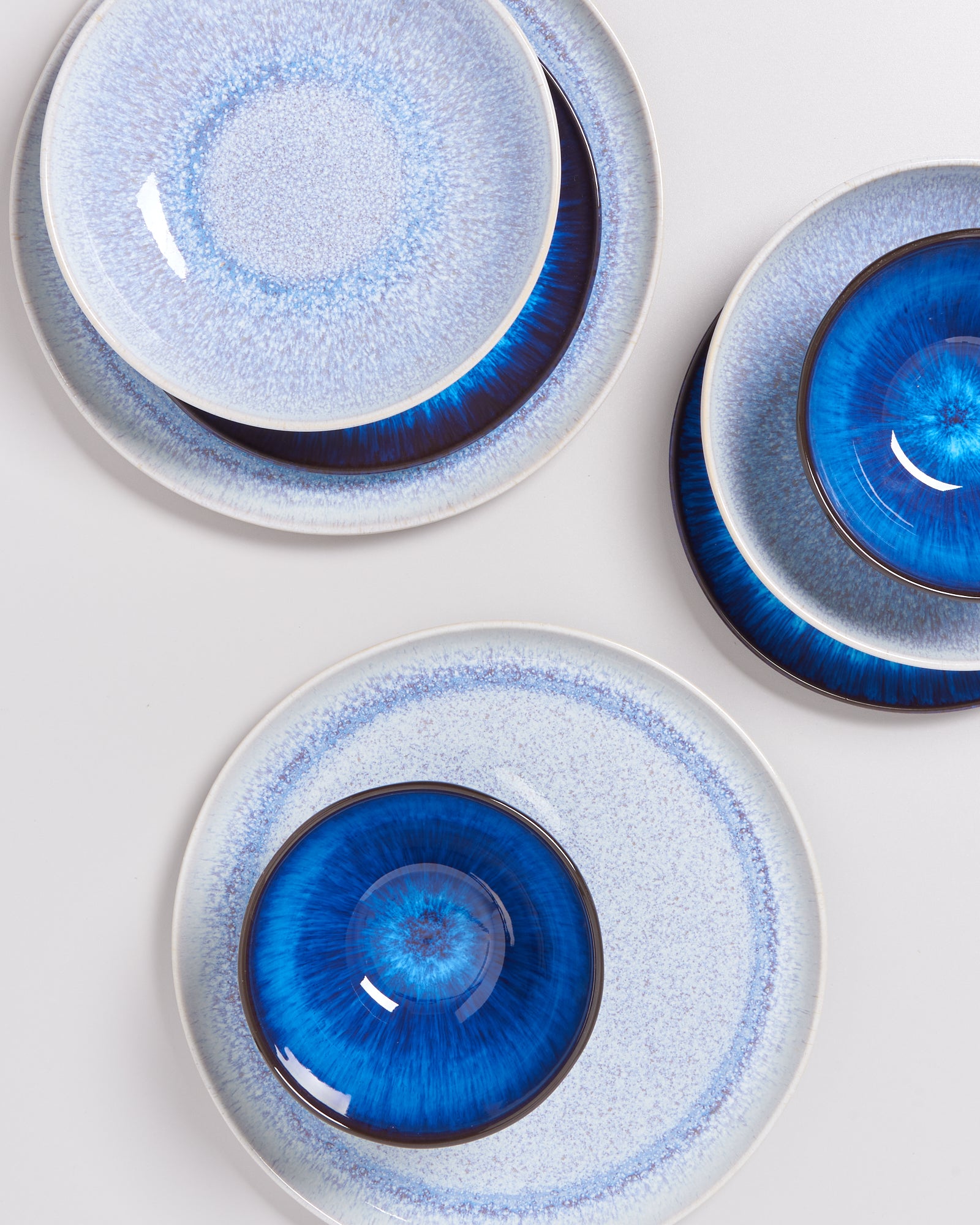Verschiedene Teller mit blauer und weißer Musterung auf hellem Hintergrund, teilweise überlappend angeordnet.