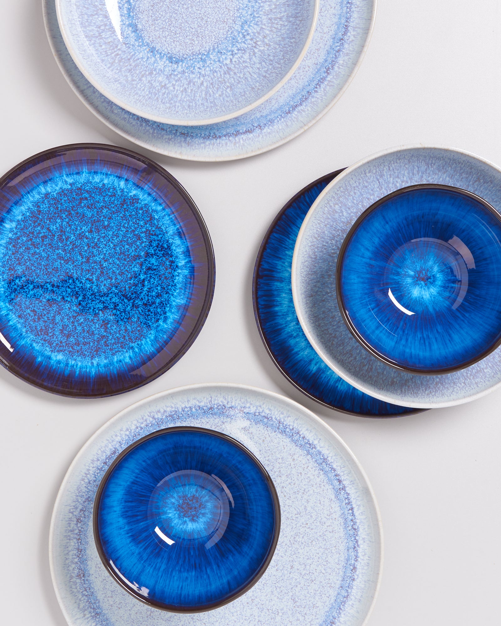 Fünf Porzellanteller mit verschiedenen Blautönen und Mustern auf weißem Hintergrund.