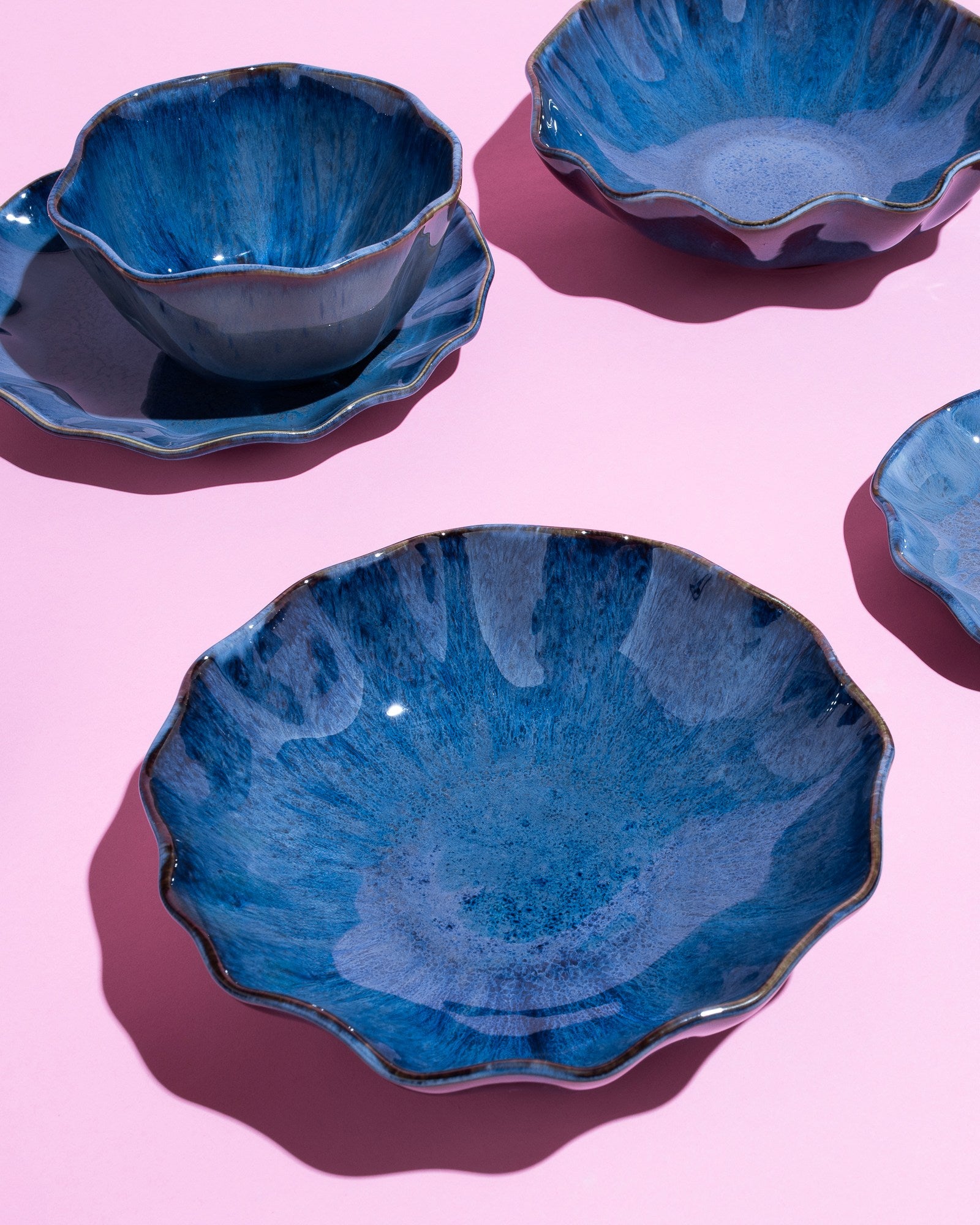 Blaue, gewellte Keramikschalen auf einem rosa Hintergrund, in einer ästhetischen Anordnung platziert.