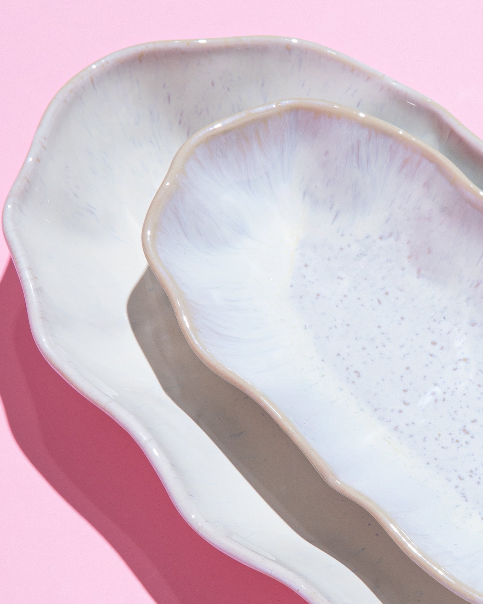 Drei überlappende Keramikteller in sanften Pastellfarben auf einem rosa Hintergrund.