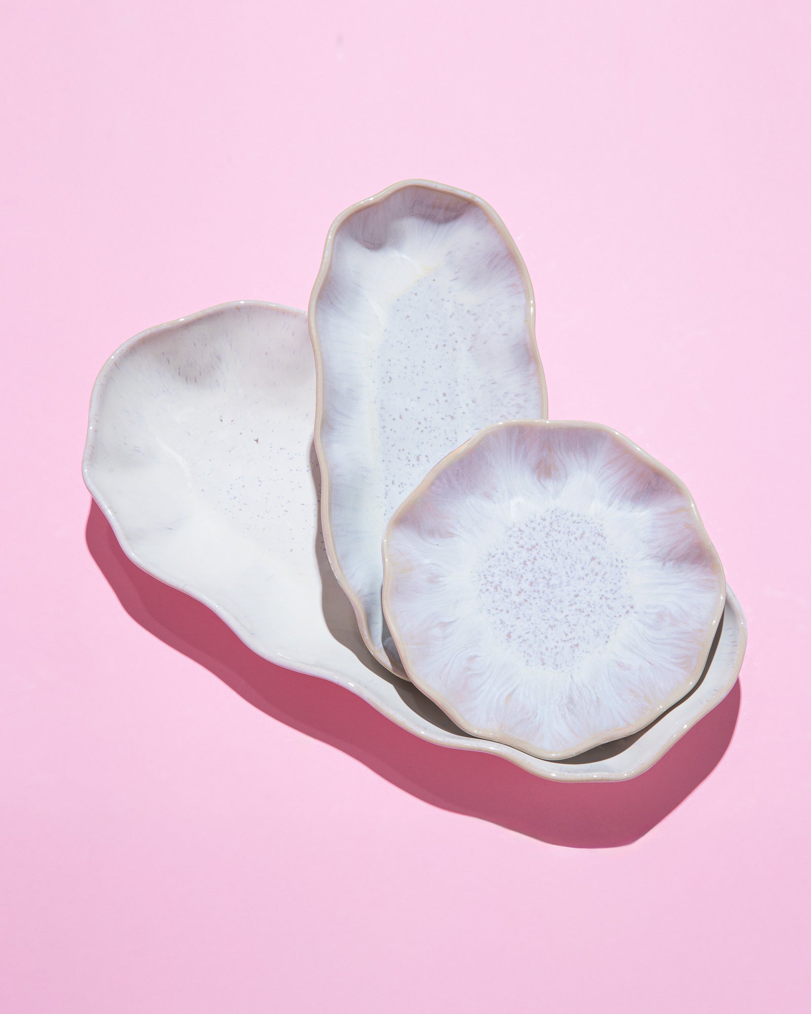 Drei dekorative Keramikteller auf einem rosa Hintergrund.