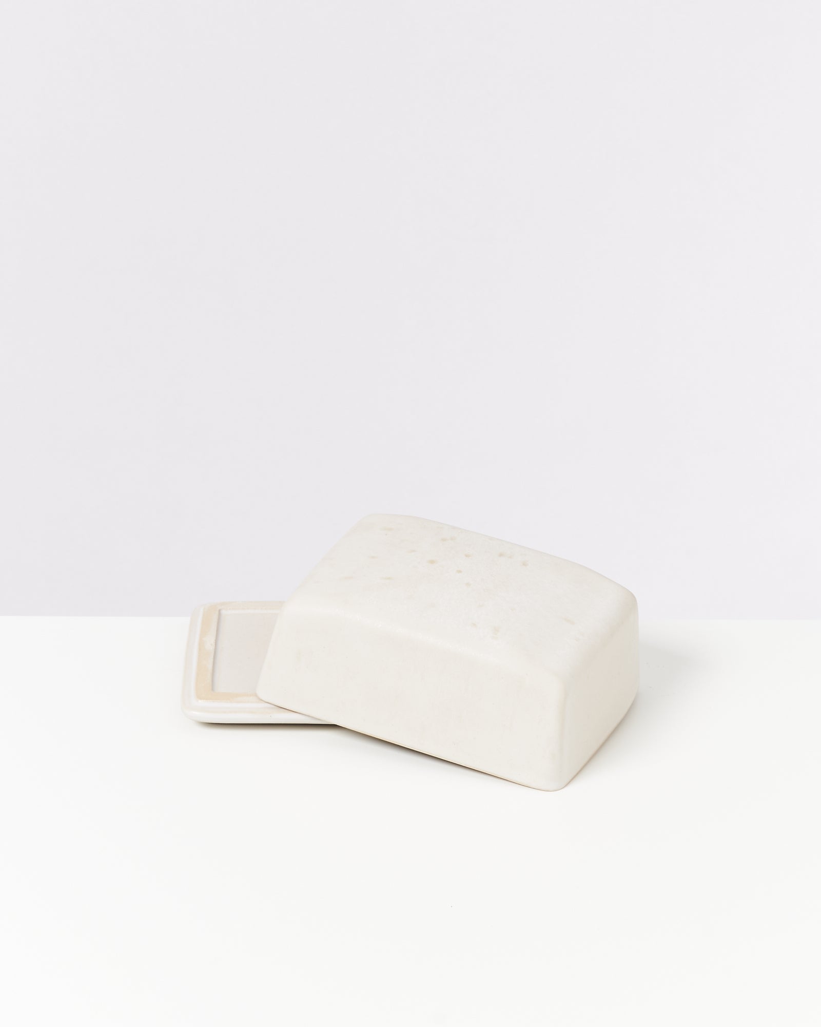 Weiße Seifenschale mit passendem Deckel auf weißem Hintergrund.